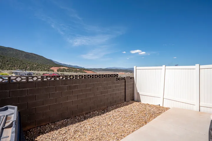 Outdoor space featuring a concrete patio, gravel landscaping, and a combination of block and white vinyl fencing
