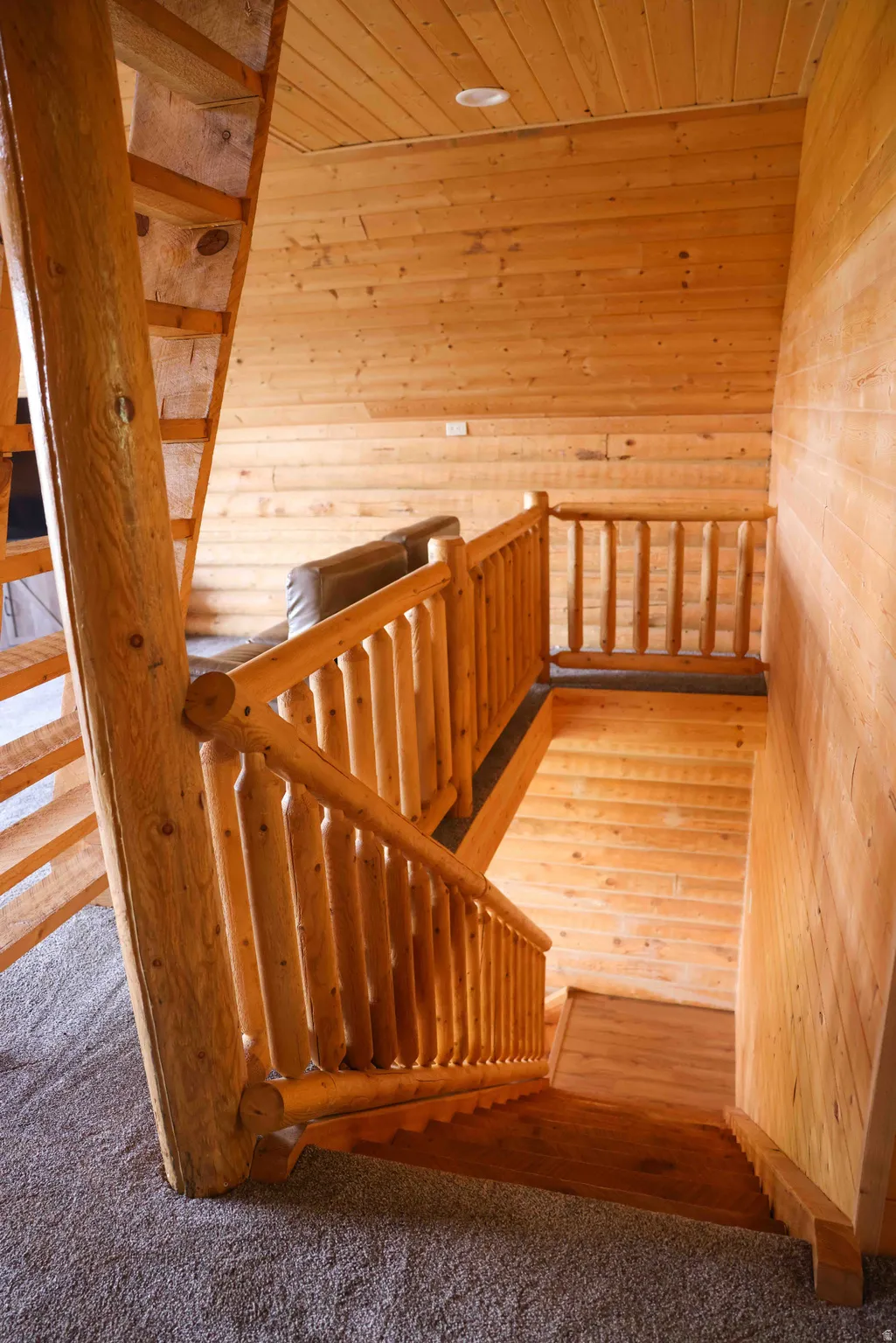 Rustic staircase featuring log-style railings and banisters