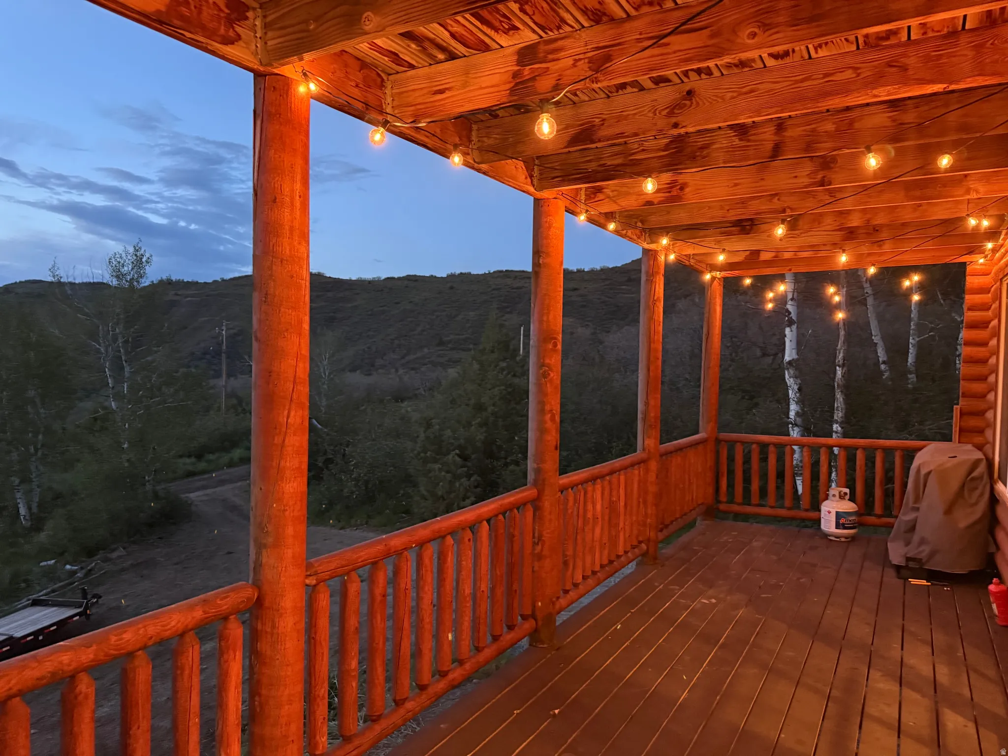 Expansive covered deck featuring a wood-finish floor, wood posts, and string lighting