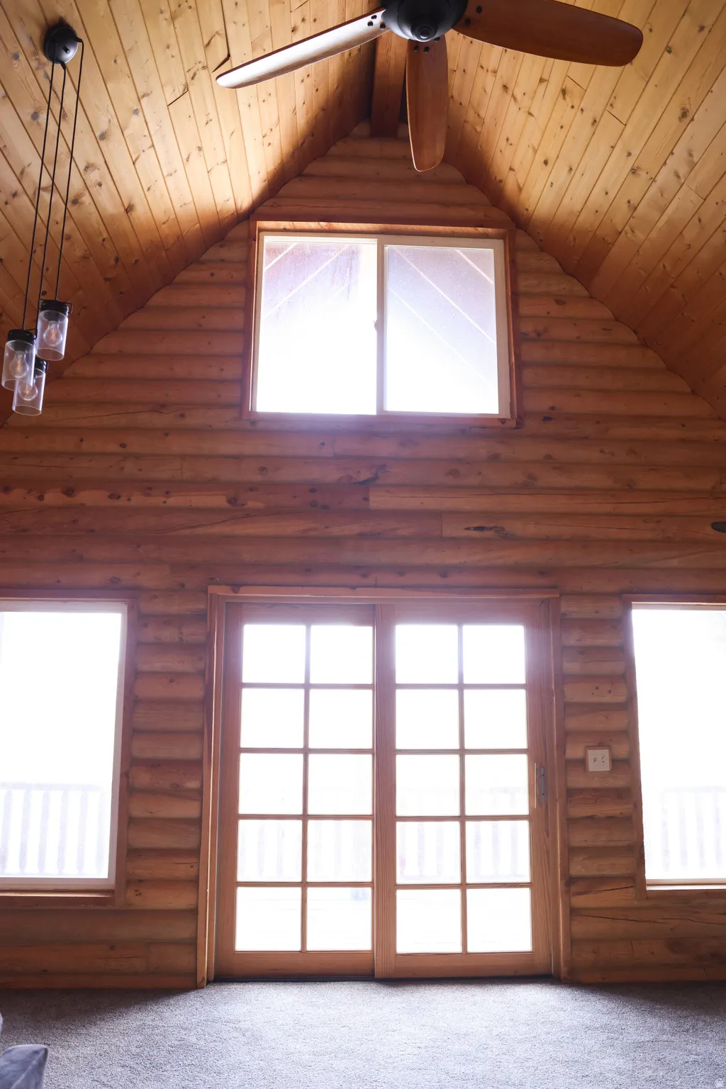 Vaulted wood-paneled ceiling with an exposed beam and ceiling fan