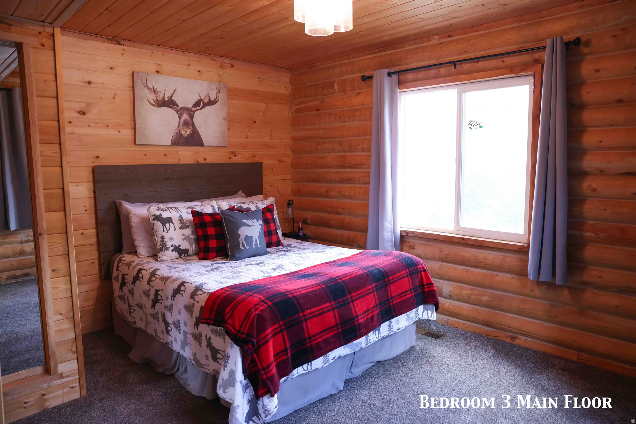 Carpeted room featuring natural wood paneling and a large window