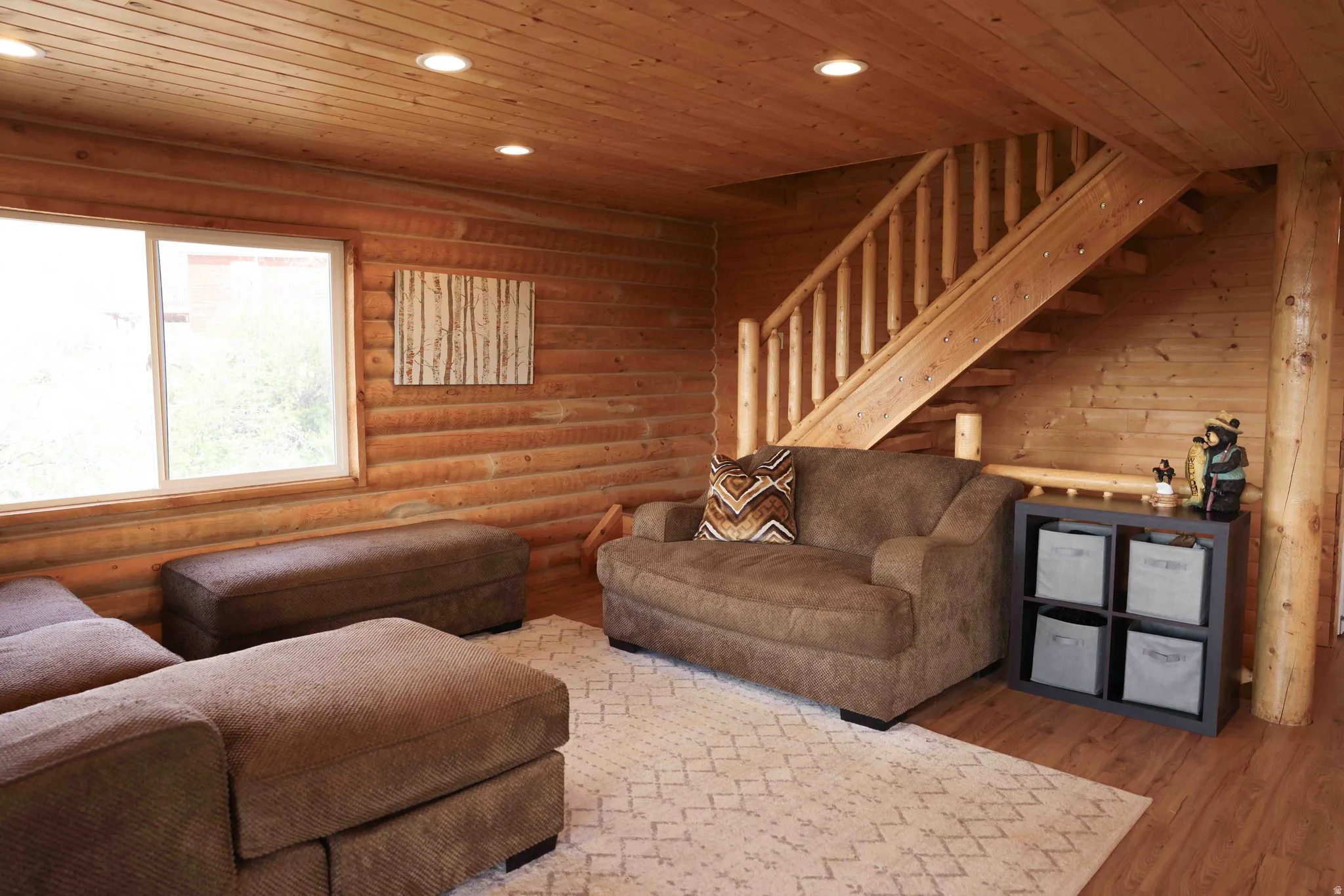 Wood-paneled interior featuring a prominent staircase with wood balusters, a large window, recessed ceiling lighting, and wood-finish flooring