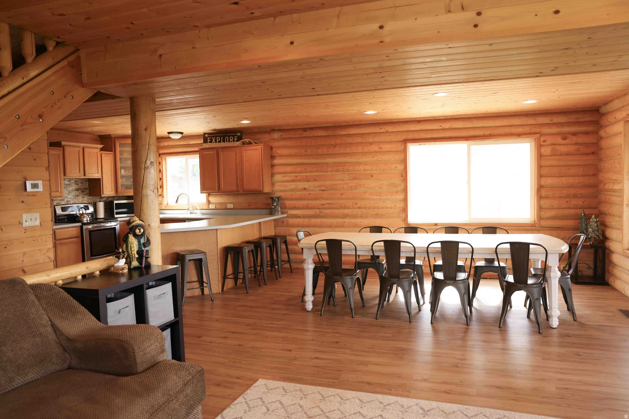 Open-concept living space featuring log walls, wood-finish flooring, and a dining area with a large table