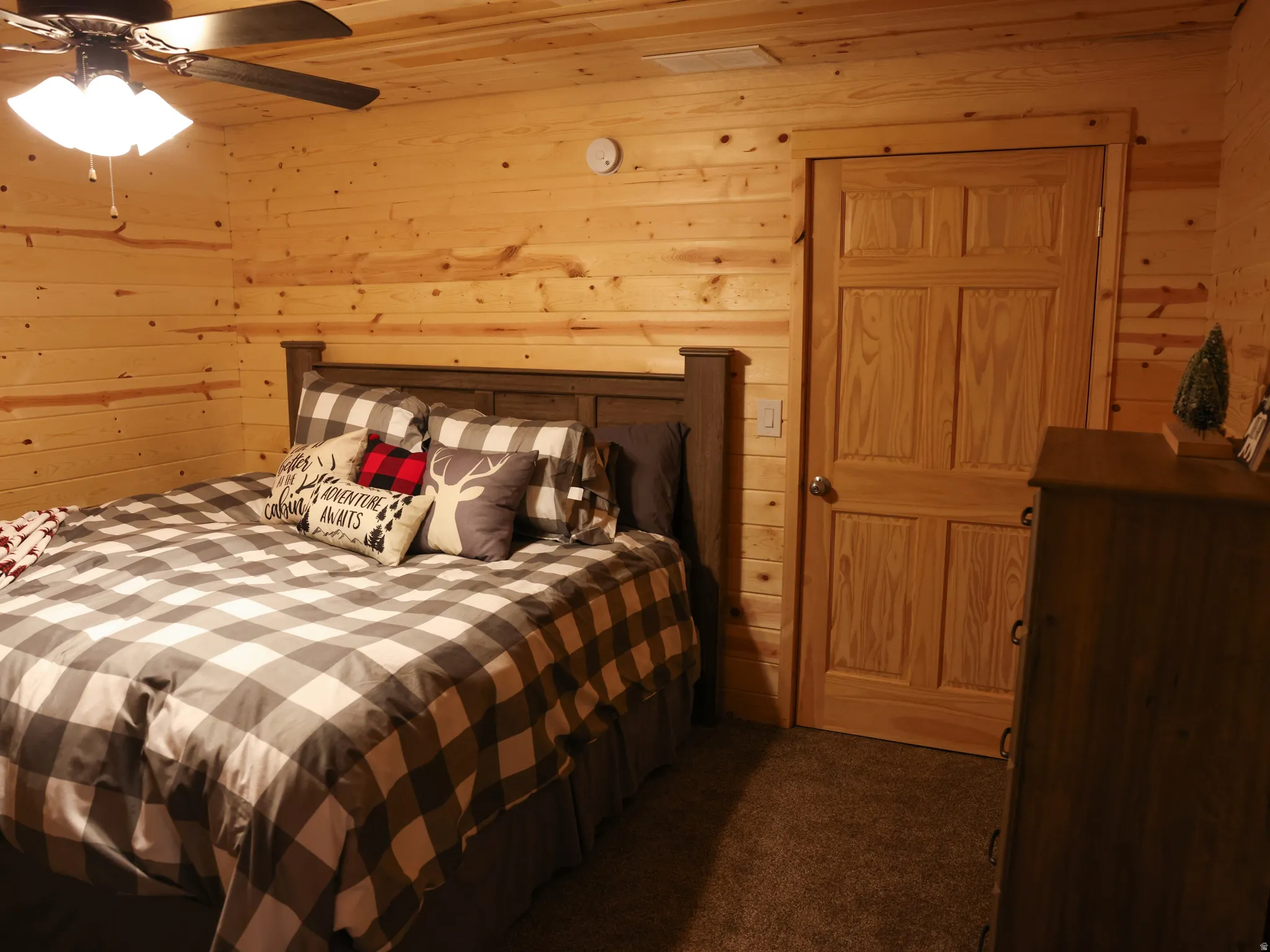 Room featuring wood-plank walls and ceiling, a paneled door with wood trim, and textured carpeting