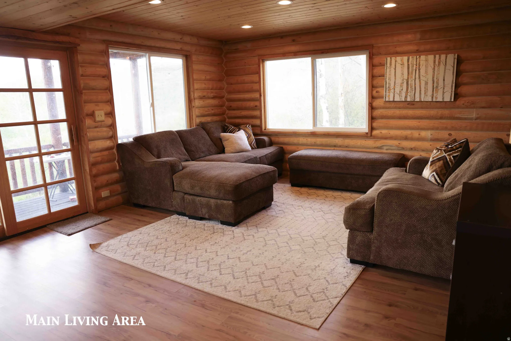 Living area featuring log walls, wood-finish flooring, a wood-paneled ceiling, recessed lighting, and multiple windows