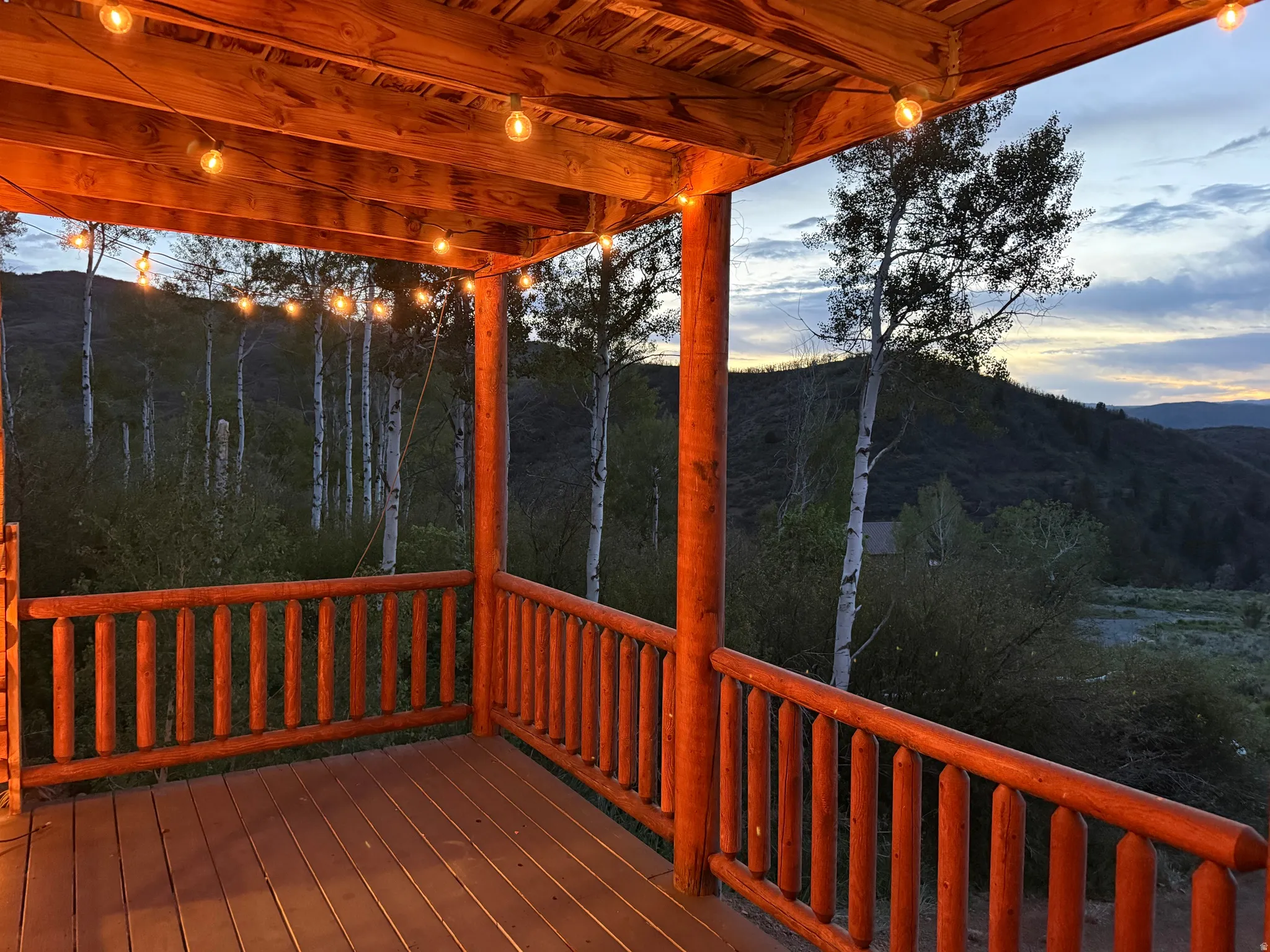 Covered outdoor deck featuring exposed wood beams and string lighting