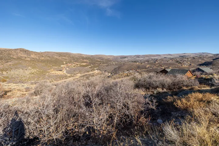 Fall views. Expansive hillside landscape featuring a clear blue sky, distant mountain ranges, and scattered residential structures