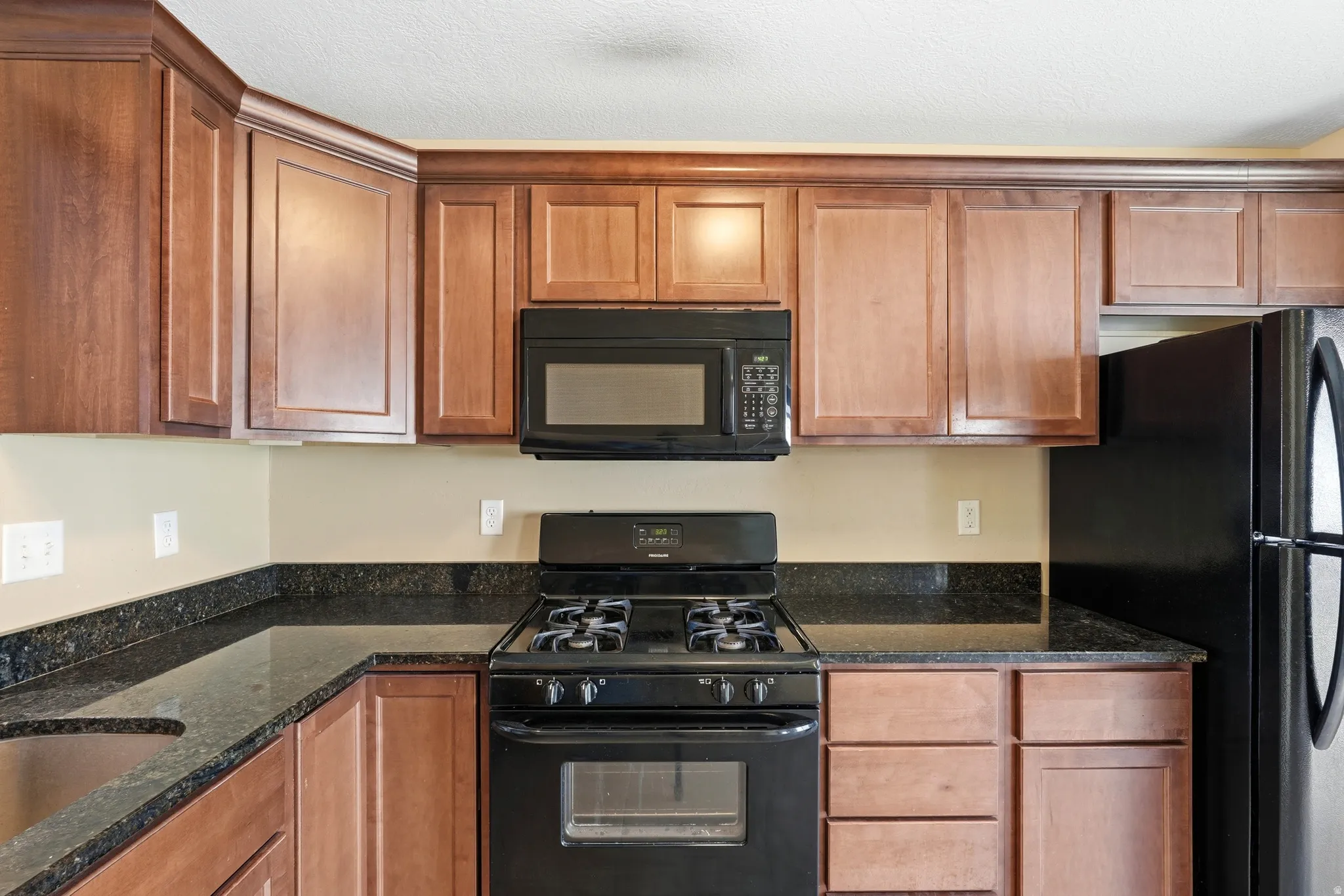 Kitchen featuring wood cabinetry, black appliances, a pass-through window, and a tile floor