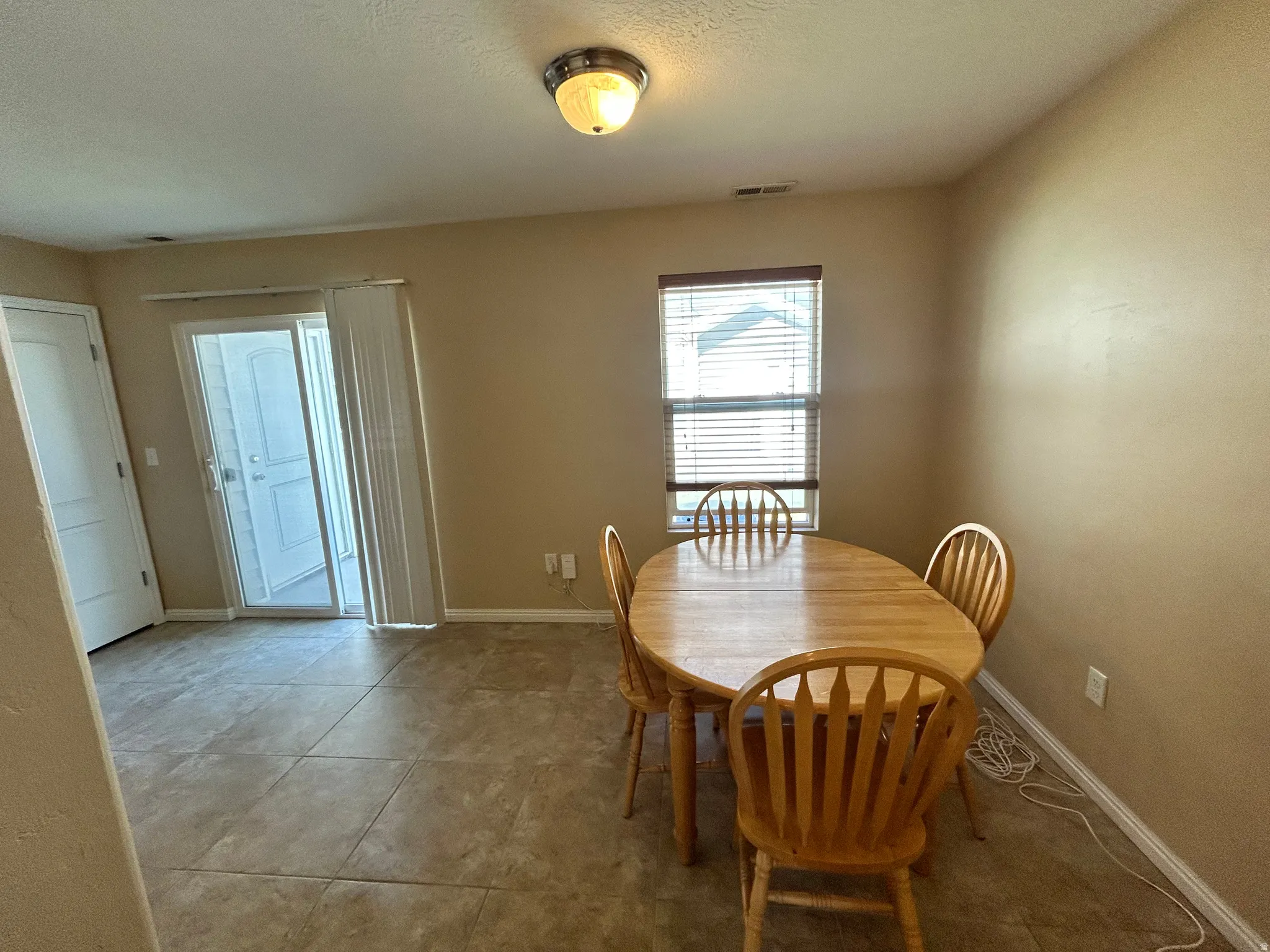 Dining area featuring tile flooring, a sliding glass door, and a window with blinds