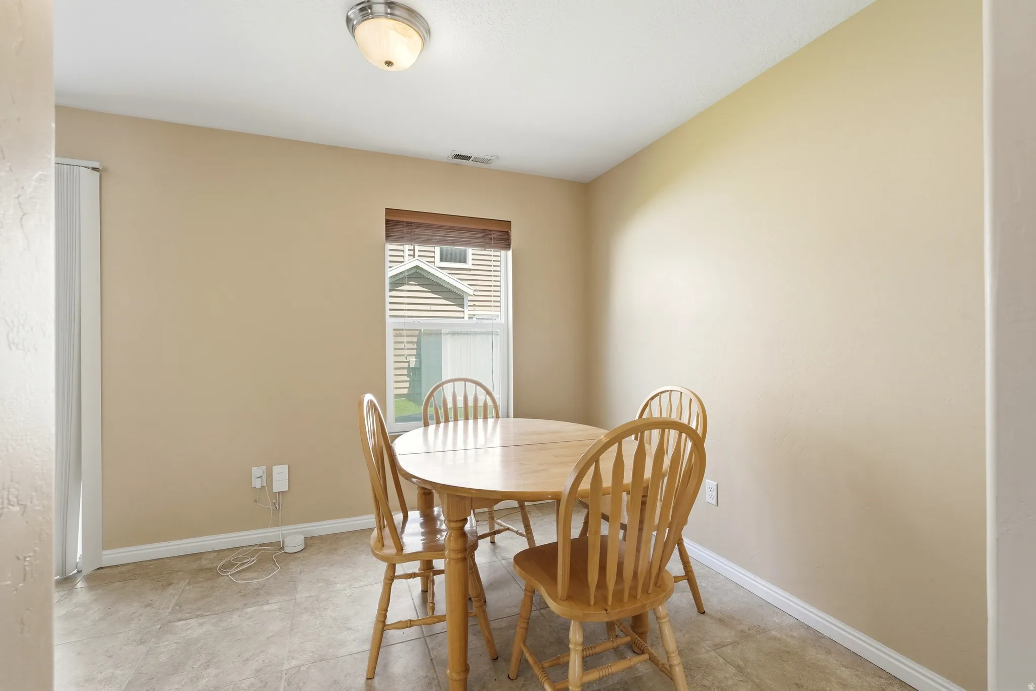 Dining area featuring a window with wood-look blinds, neutral wall paint, white baseboards, and tile flooring
