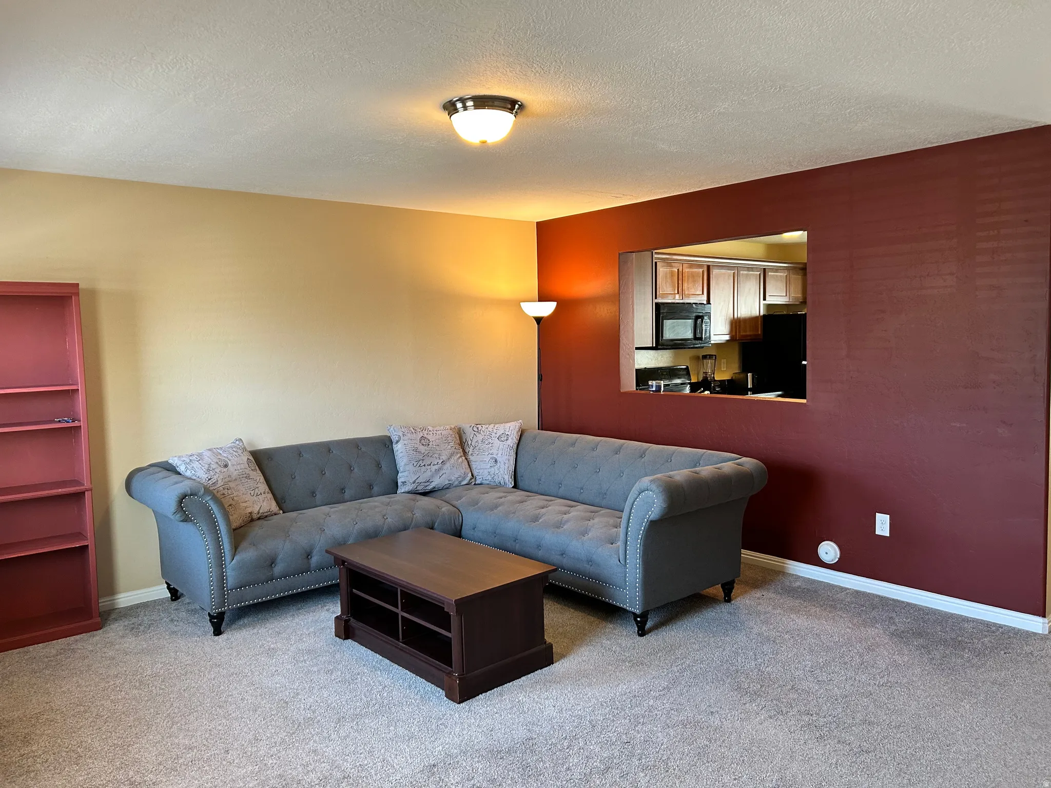 Living room featuring carpet and a pass-through window to the kitchen