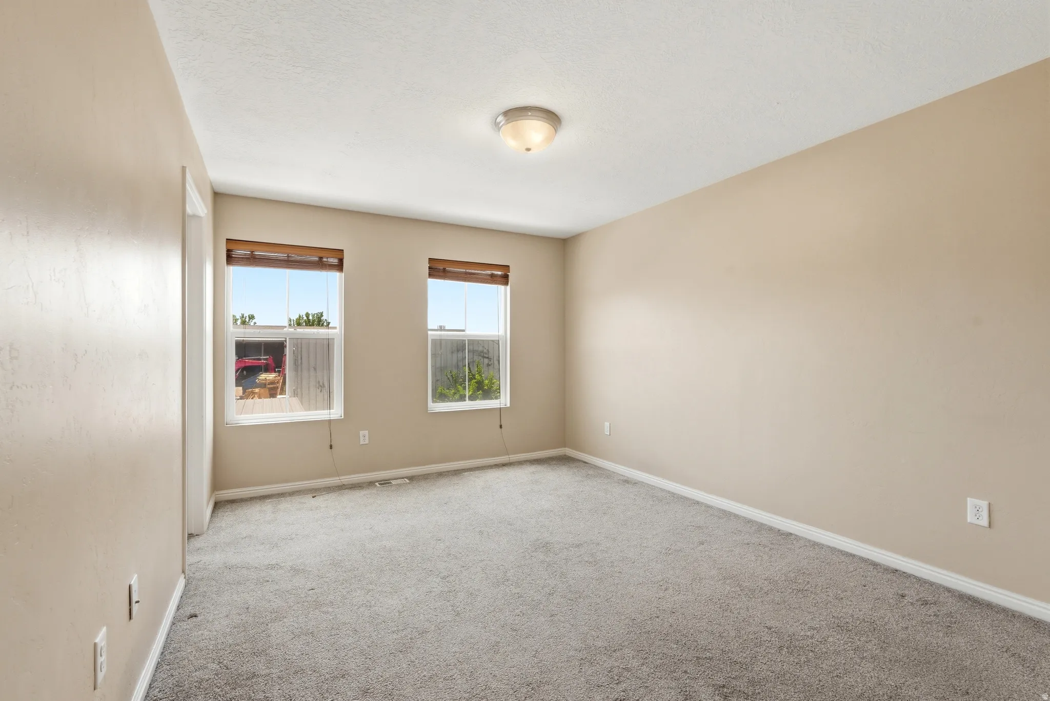 Master bedroom with neutral wall tones and textured carpeting