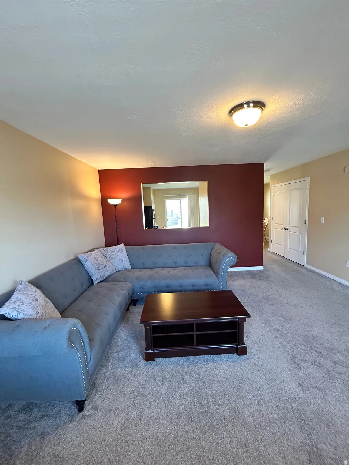 Spacious living area with carpeting and a distinct accent wall