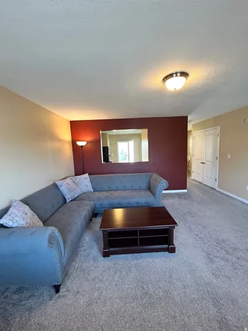 Spacious living area with carpeting and a distinct accent wall