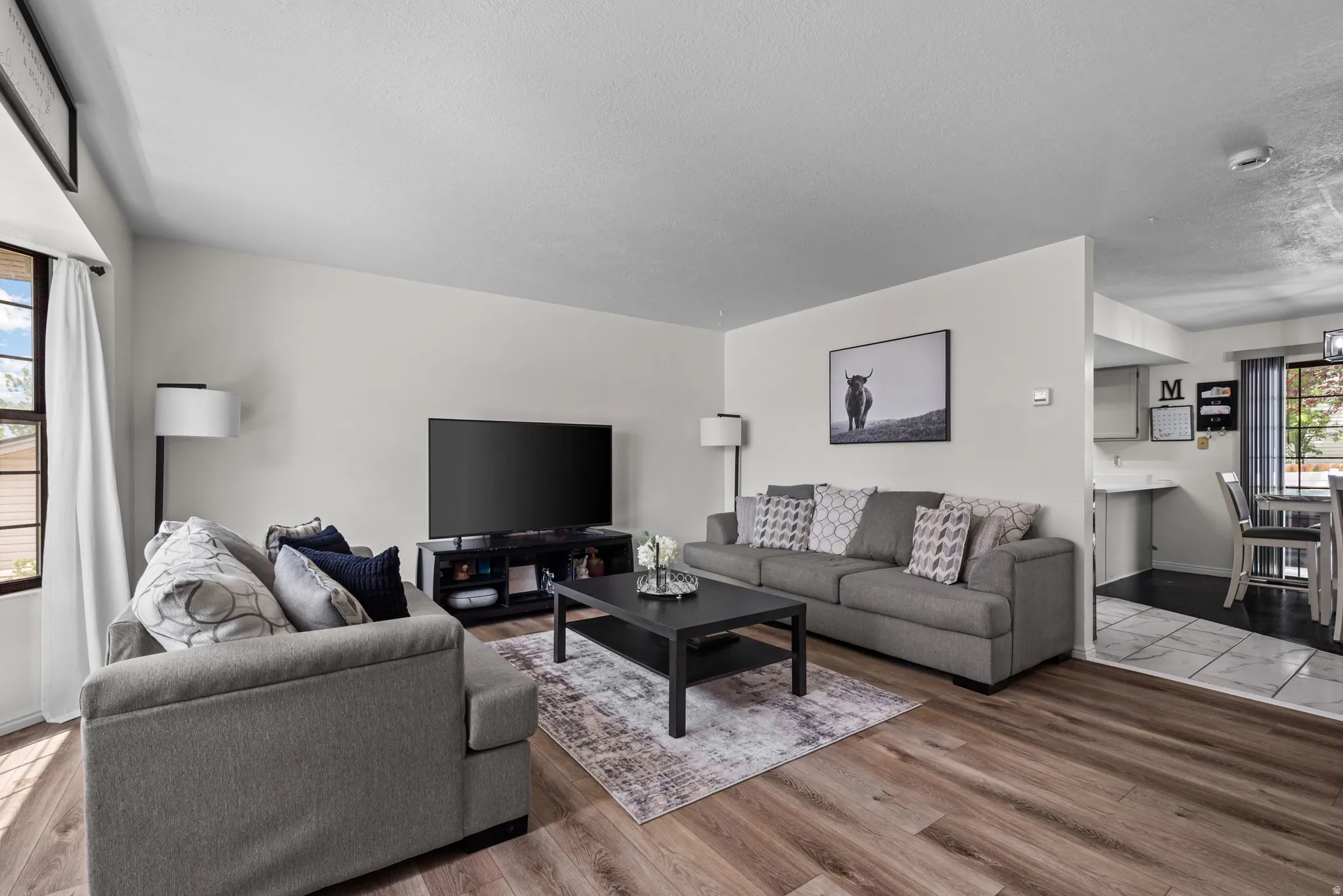 Open-concept living area with wood-finish flooring, abundant natural light, and a dedicated dining space