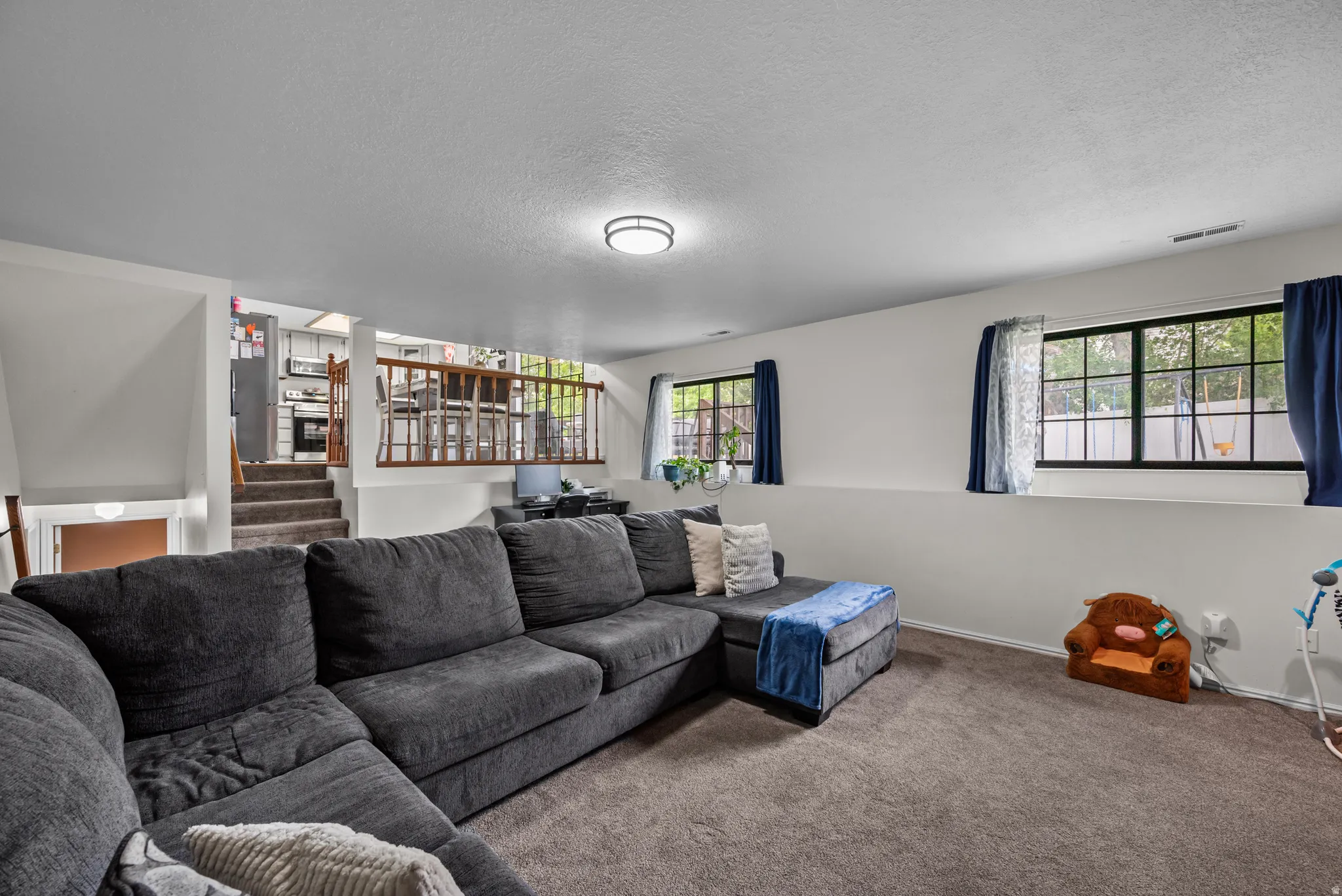 Lower-level living area with carpet flooring and two windows providing natural light