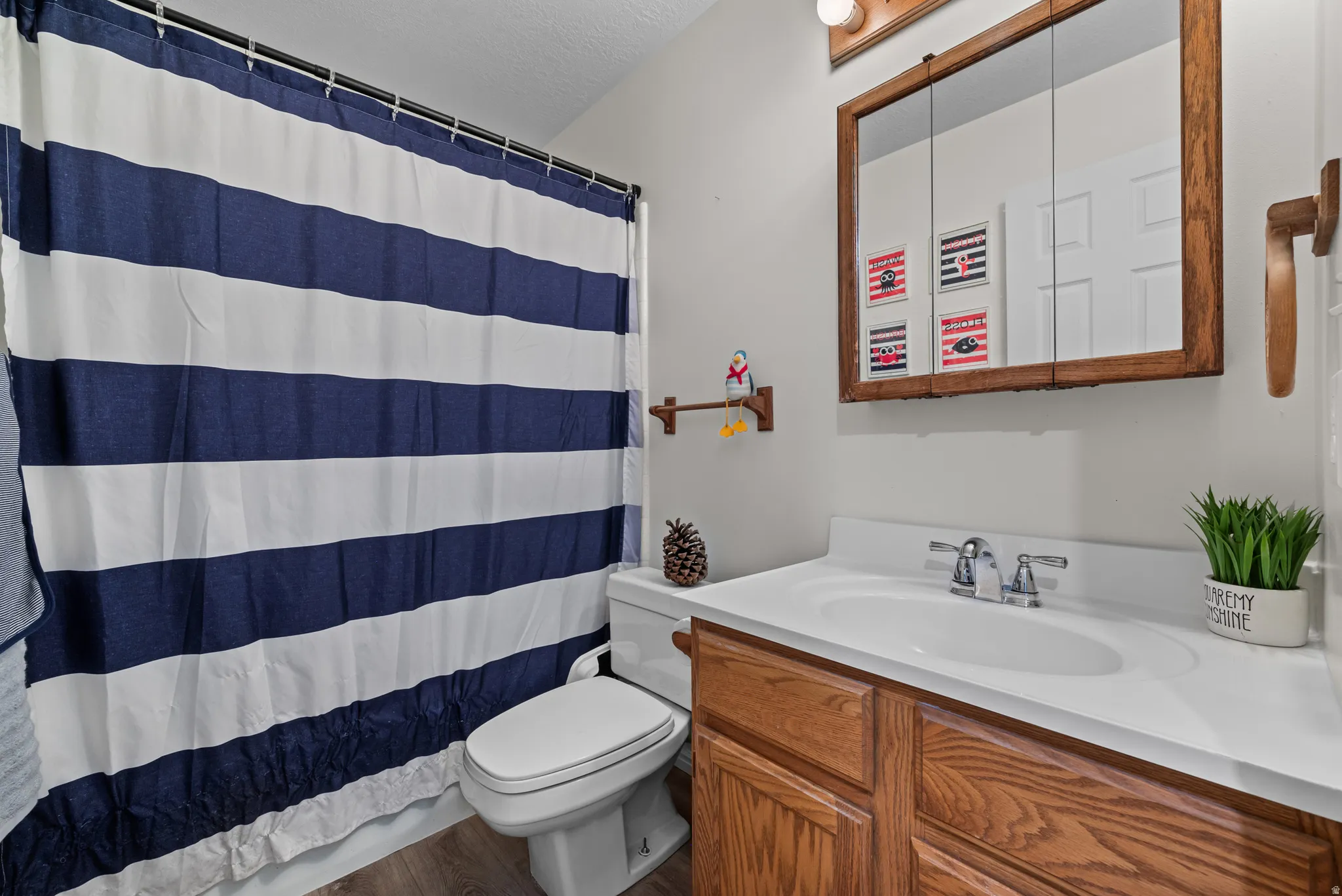 Bathroom featuring wood-finish vanity with integrated sink, chrome faucet, and wood-framed medicine cabinet