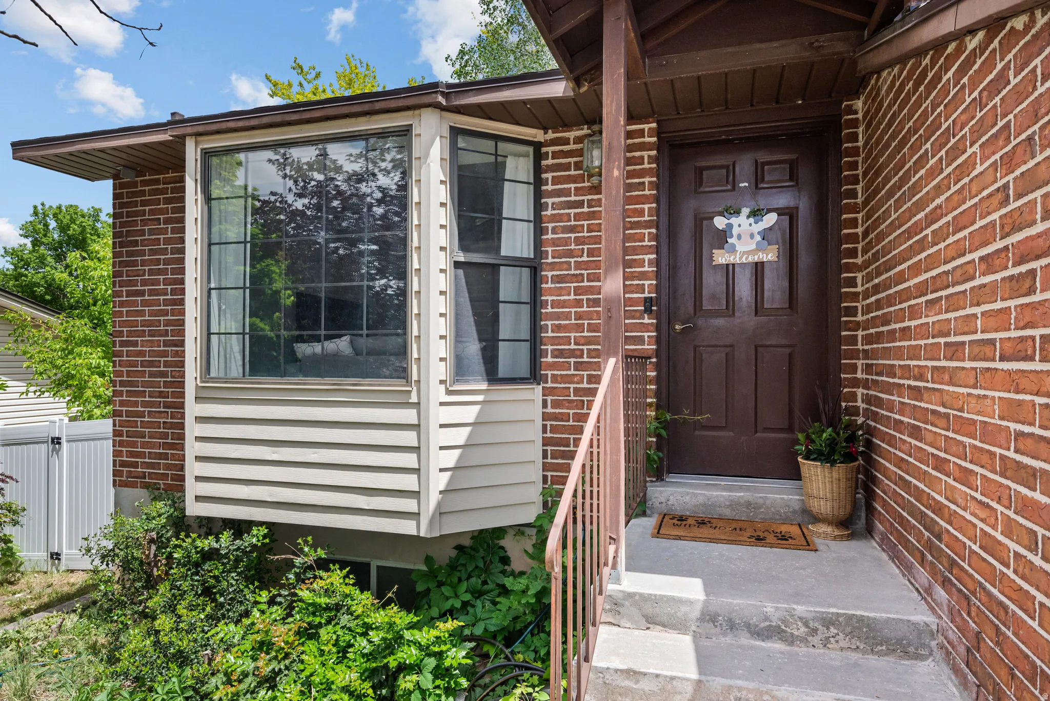 Brick exterior featuring a prominent bay window with gridded panes and a porch entrance