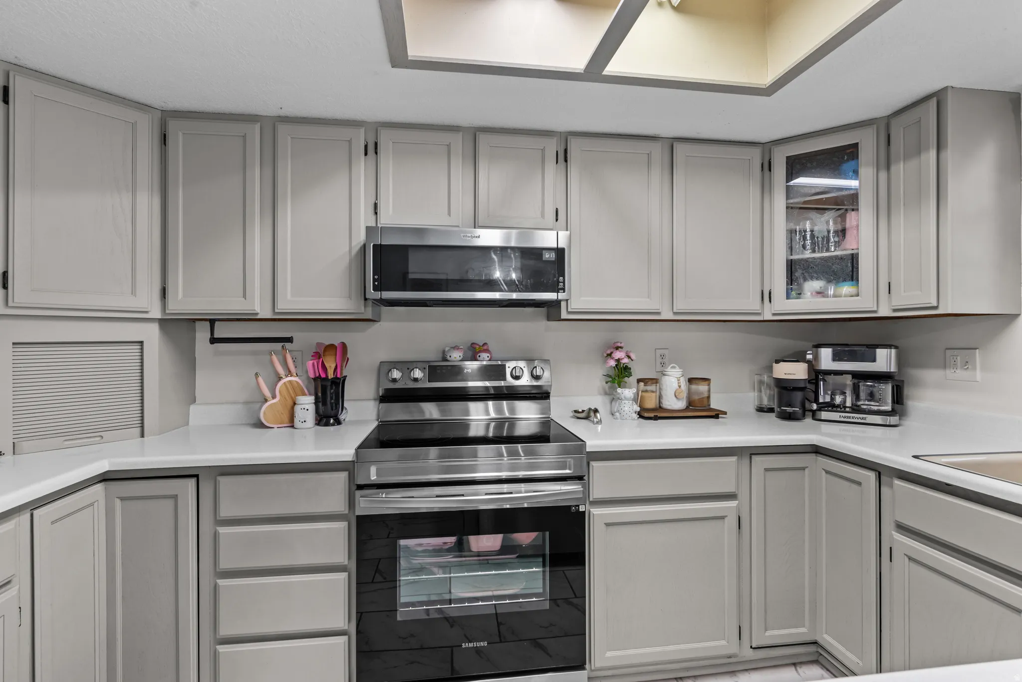 Kitchen featuring light gray cabinetry, white countertops, stainless steel appliances, and ceiling light panels
