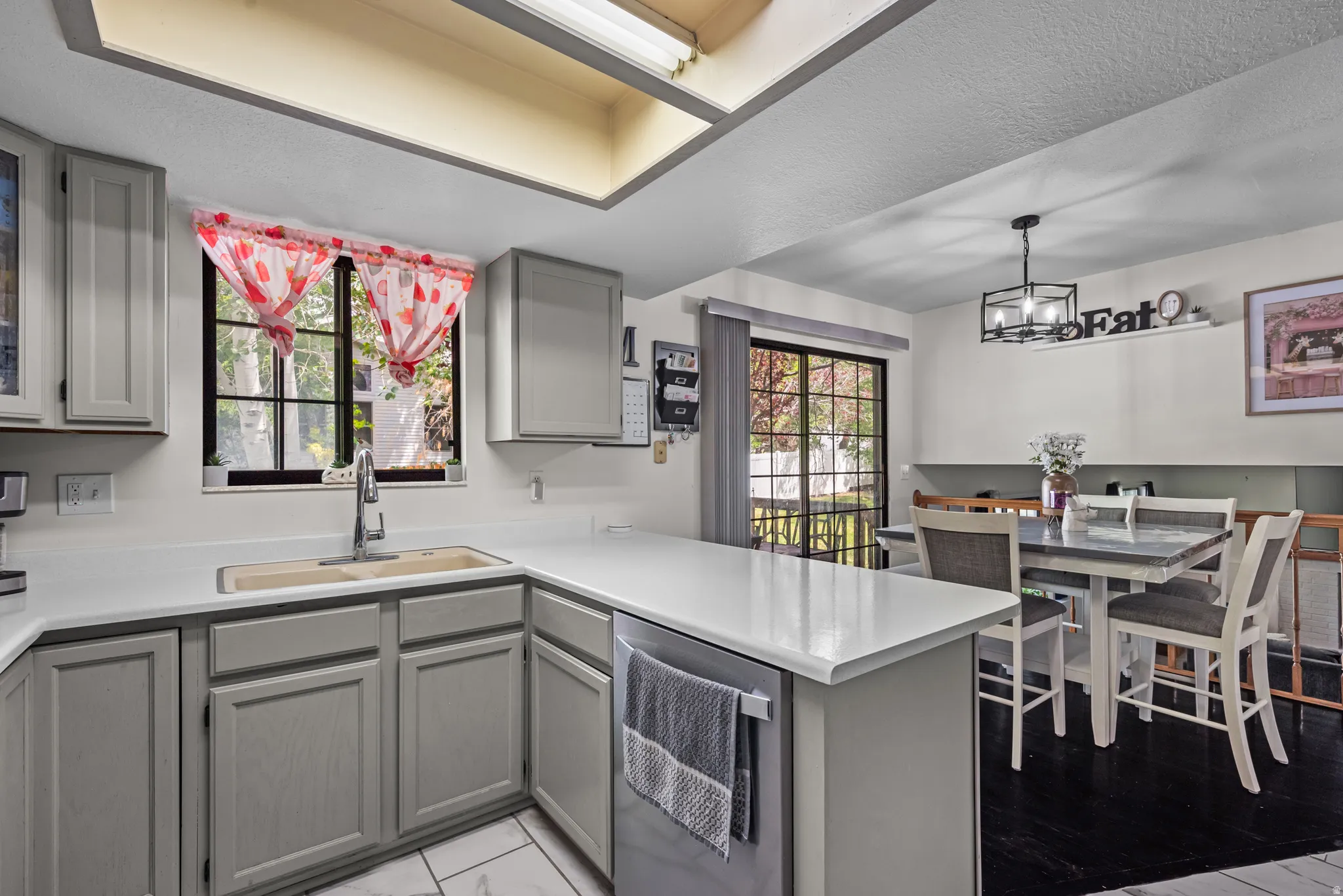 Kitchen featuring gray cabinetry, light countertops, and a double basin sink with a gooseneck faucet