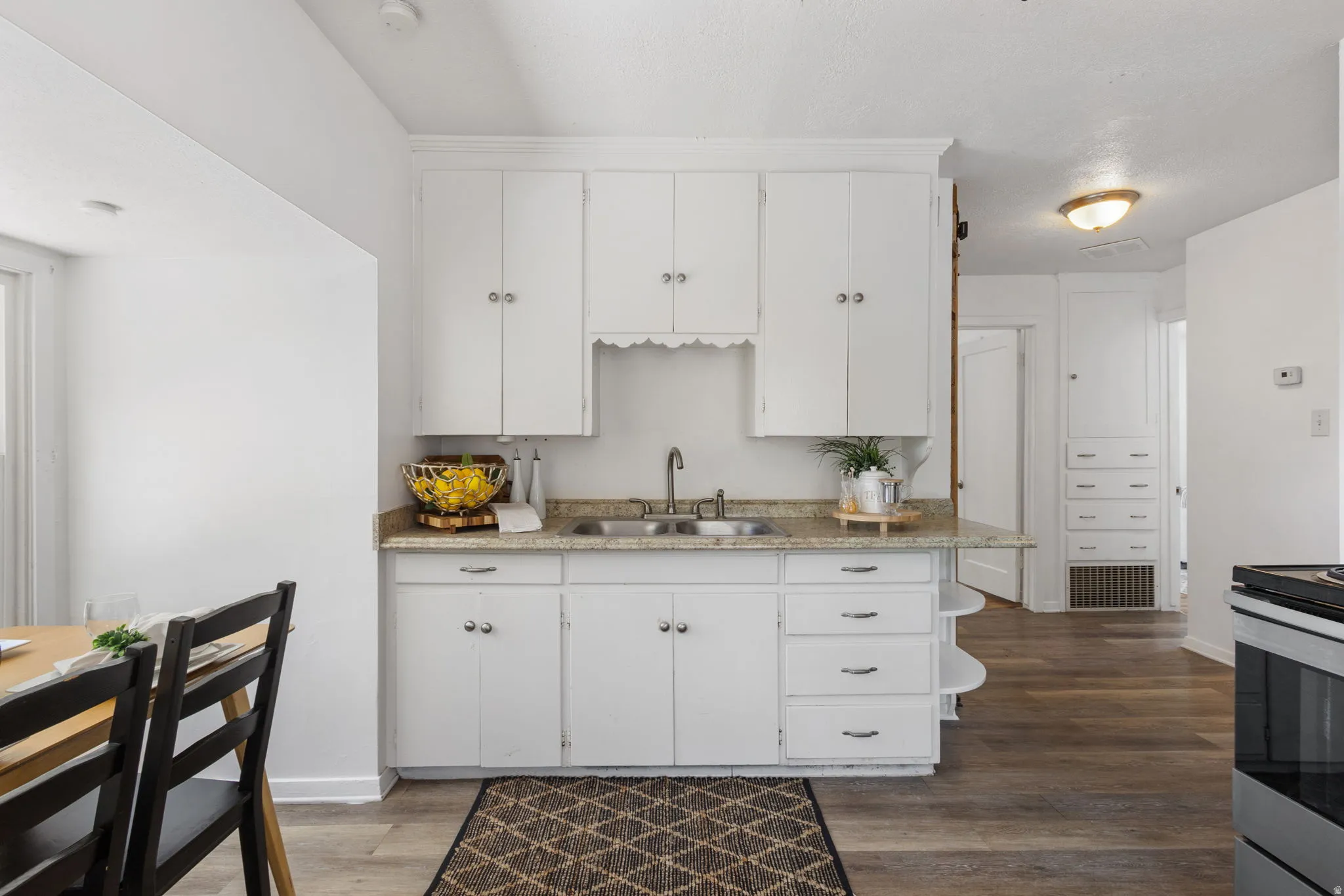 Kitchen featuring white cabinetry, a dual basin stainless steel sink, and a light-toned countertop