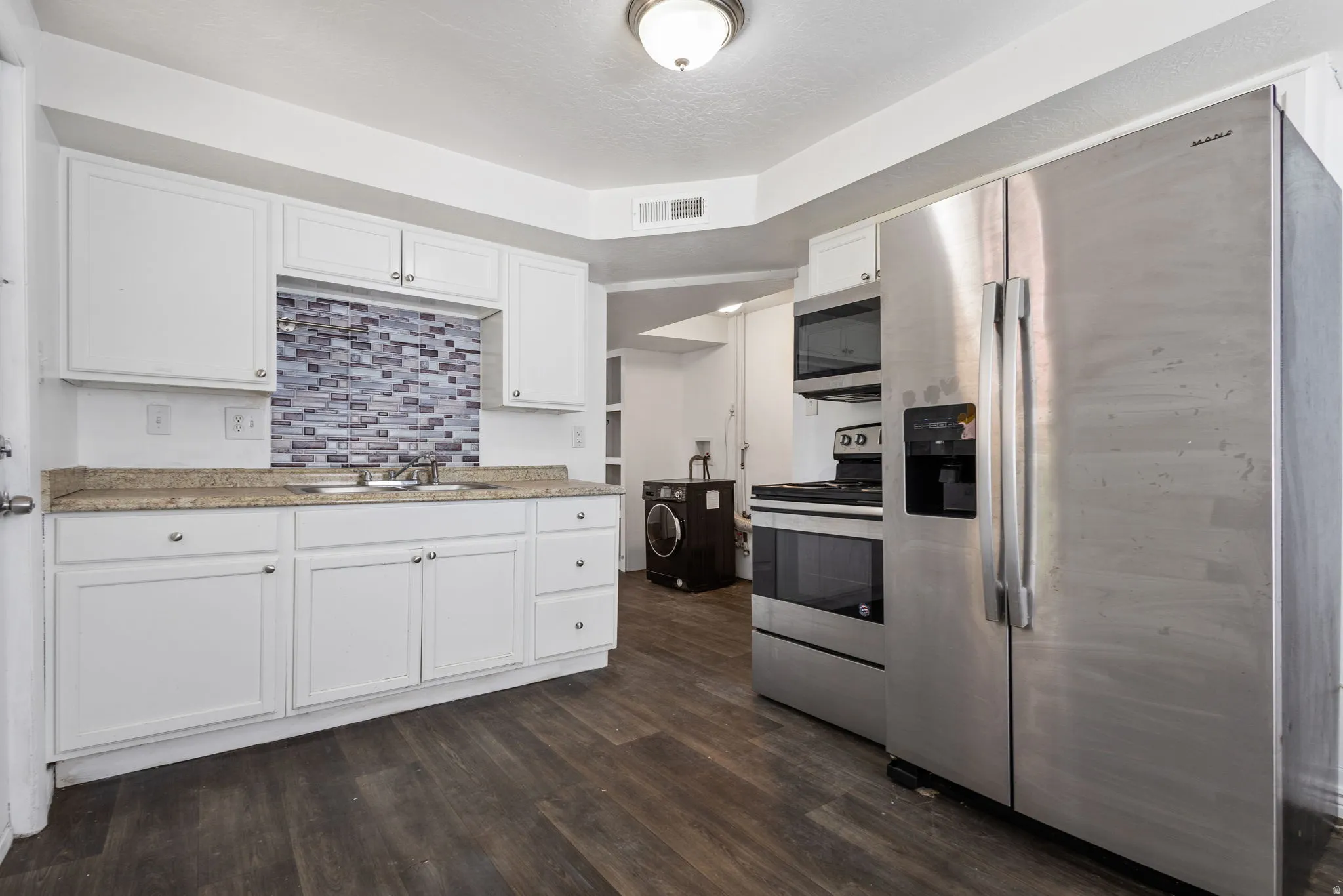 Kitchen featuring white cabinetry, light countertops, and a mosaic tile backsplash