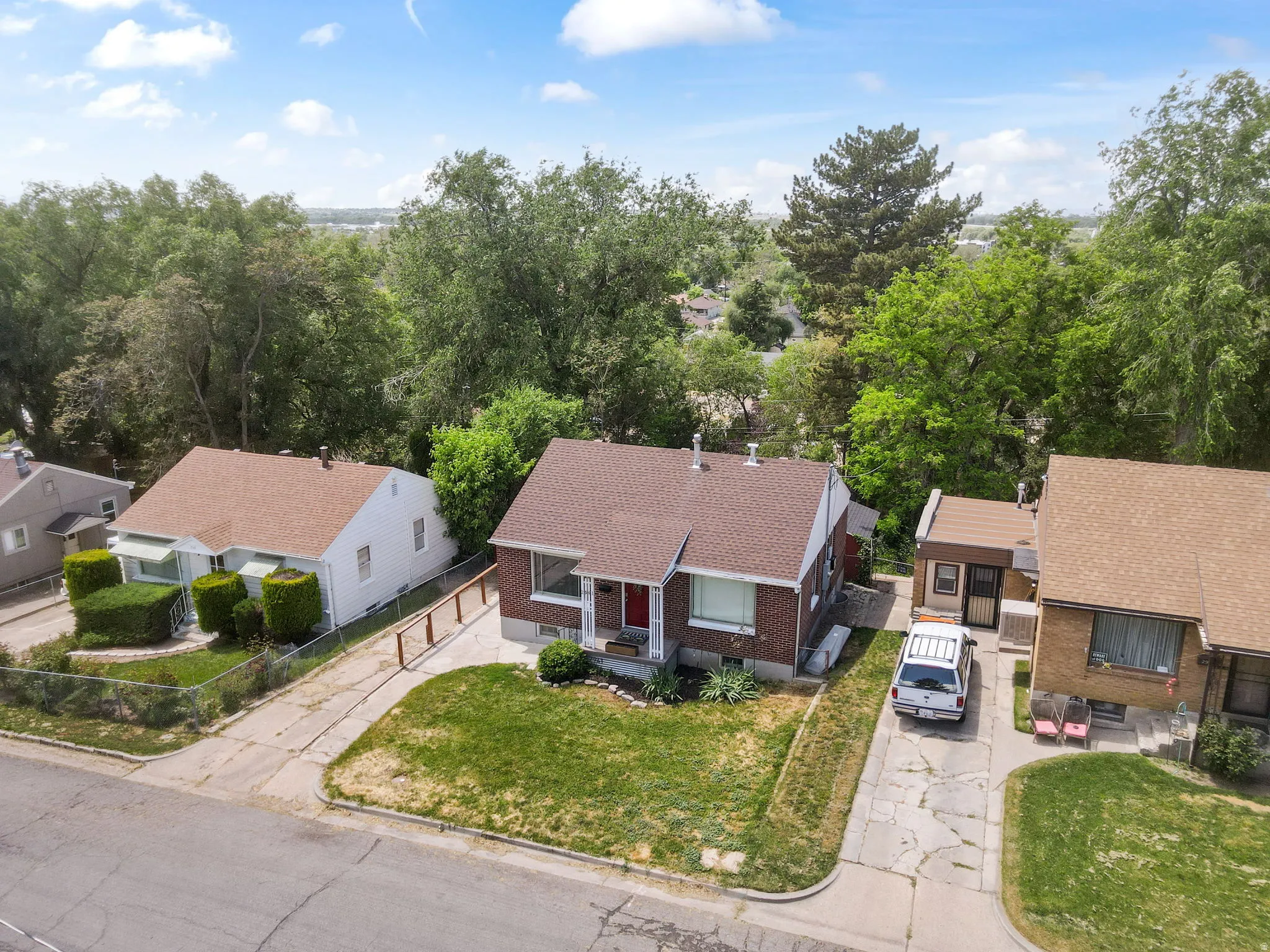 Brick-front home featuring an asphalt shingled roof and mature front yard landscaping
