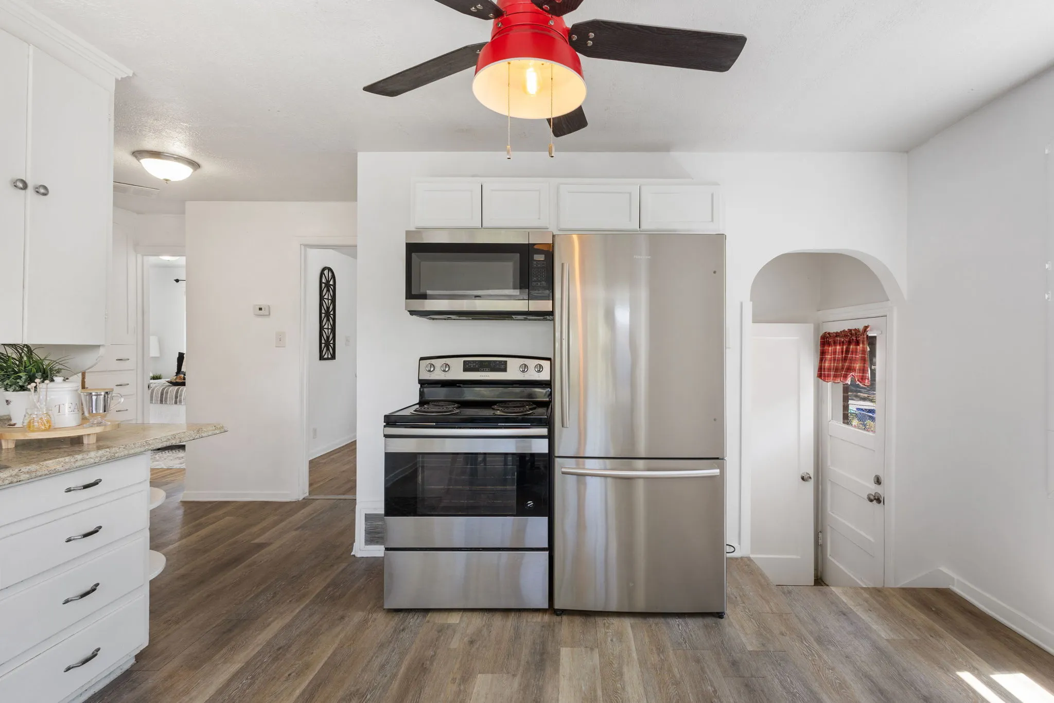 Kitchen featuring LVP flooring, white cabinetry, stainless steel appliances, and a ceiling fan with integrated lighting