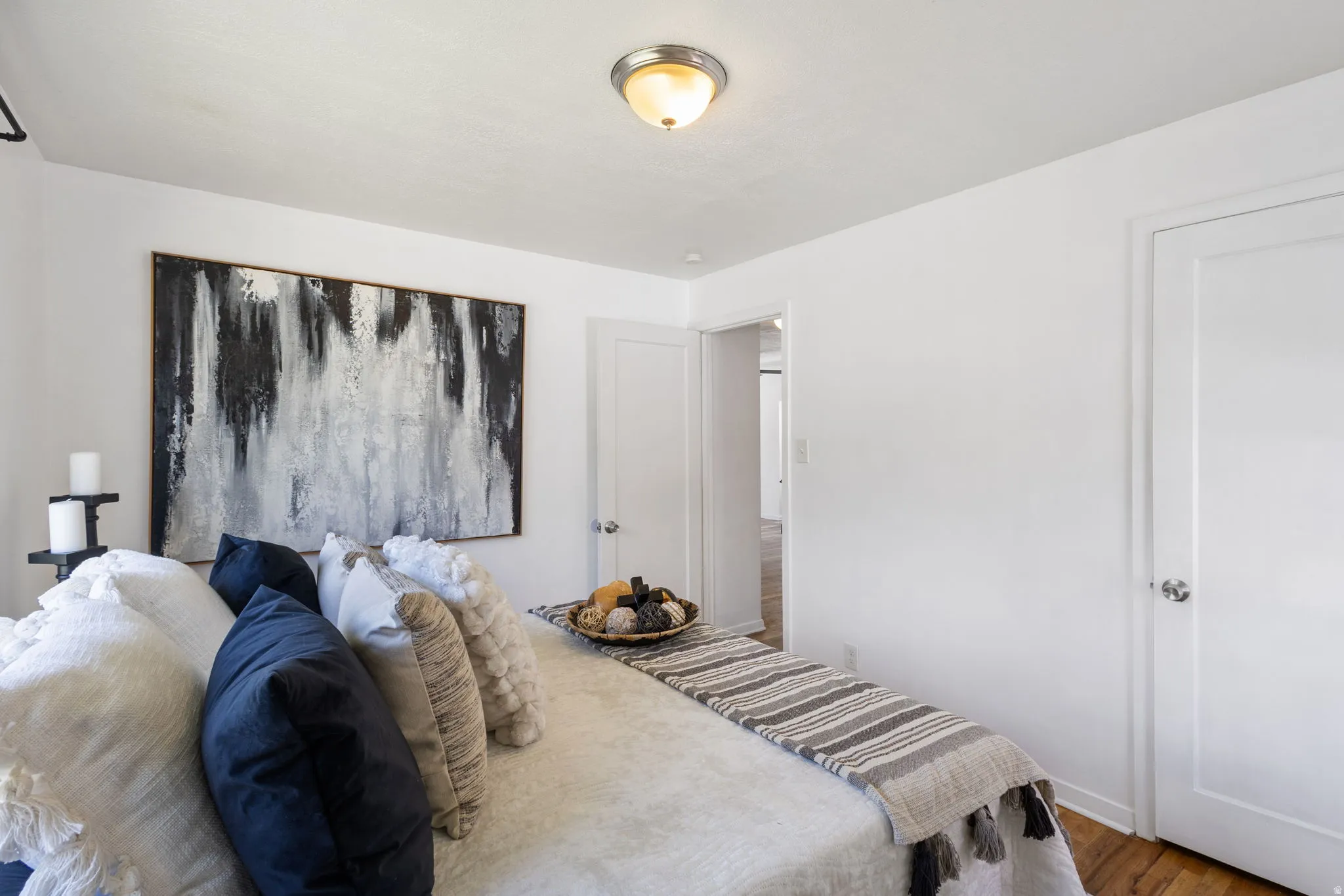 Bright bedroom featuring a flush-mount ceiling light, white painted walls, and hardwood flooring