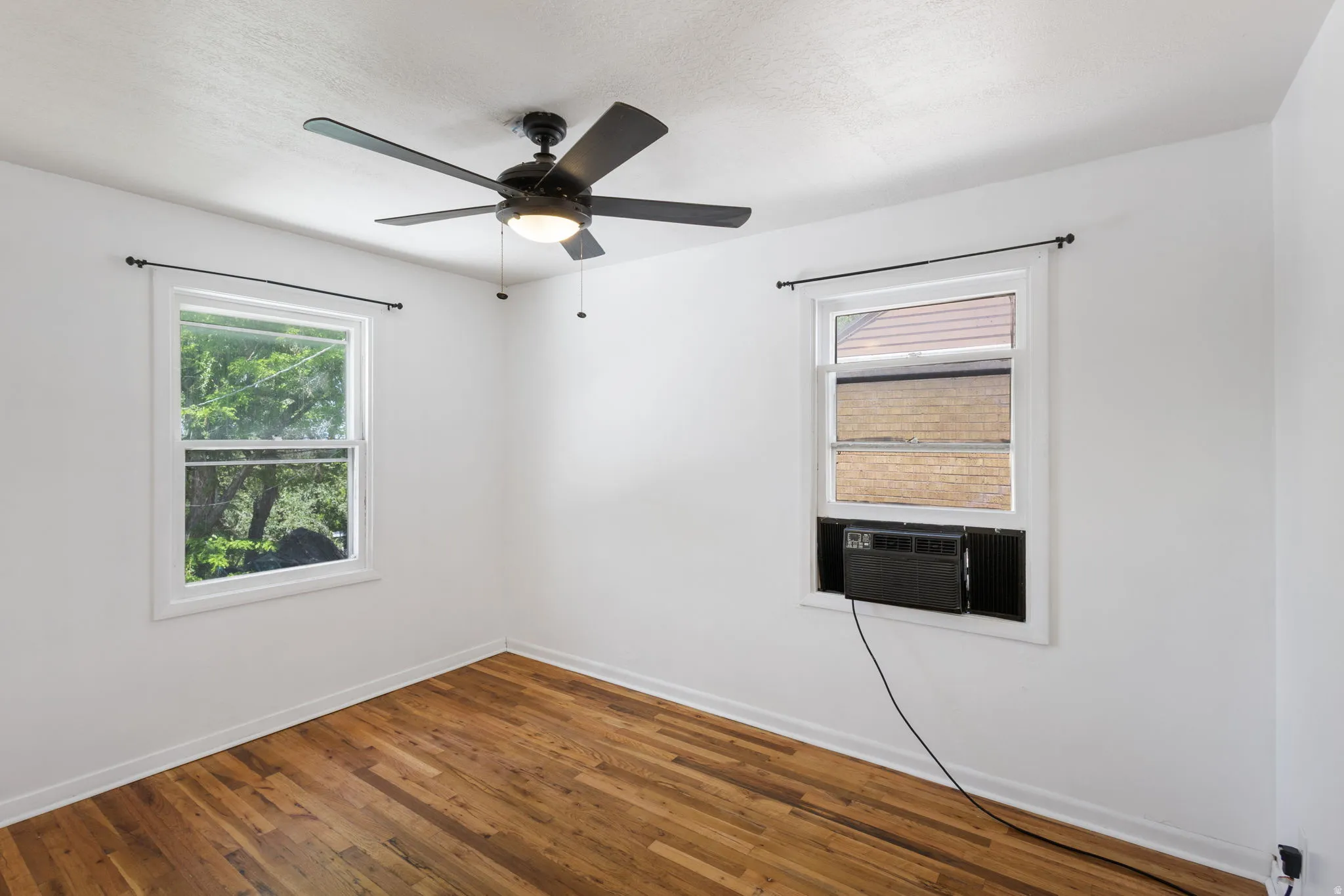 Bedroom featuring hardwood flooring, white walls, and a ceiling fan