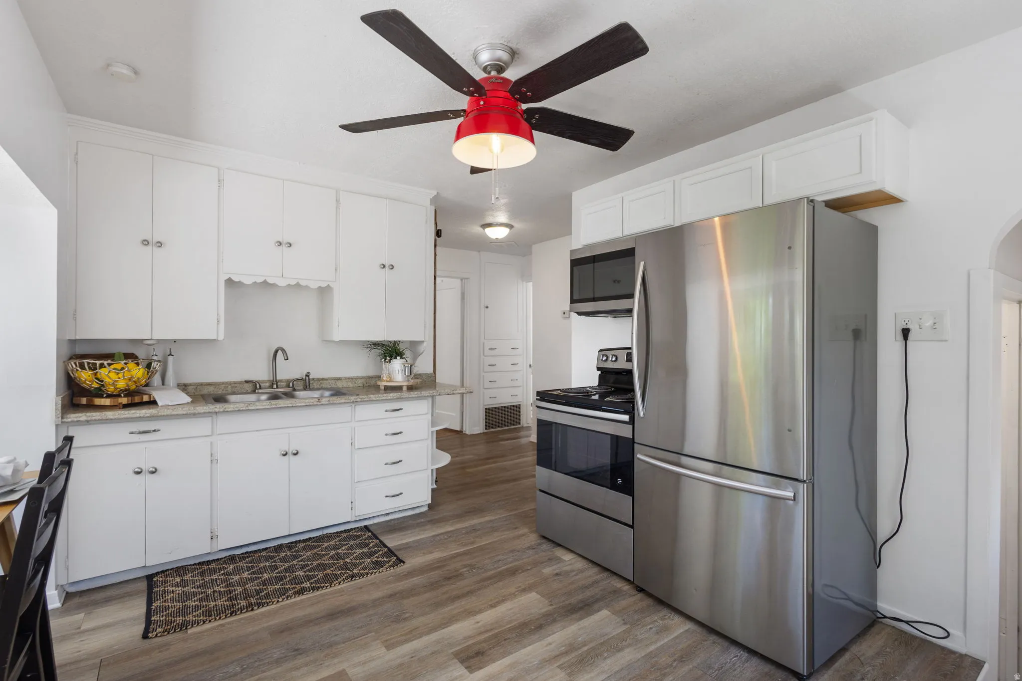 Kitchen featuring LVP flooring, white cabinetry, a stainless steel refrigerator, stainless steel range, and a ceiling fan with light fixture
