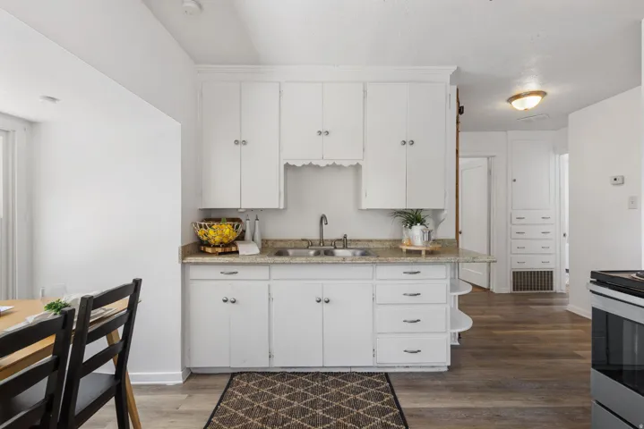Kitchen featuring white cabinetry, a dual basin stainless steel sink, and a light-toned countertop