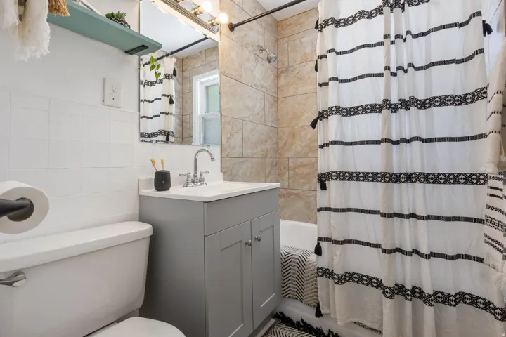 Bathroom featuring a single vanity with a gray cabinet, white countertop, and chrome faucet