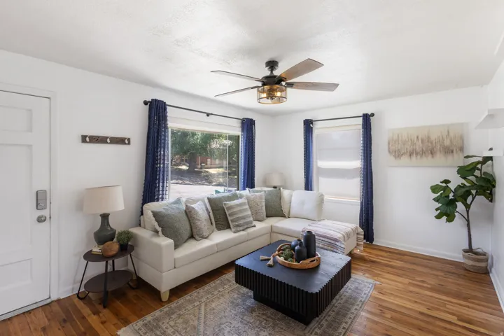 Living area featuring hardwood flooring, a ceiling fan with integrated lighting, and multiple windows