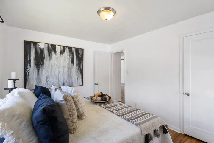 Bright bedroom featuring a flush-mount ceiling light, white painted walls, and hardwood flooring