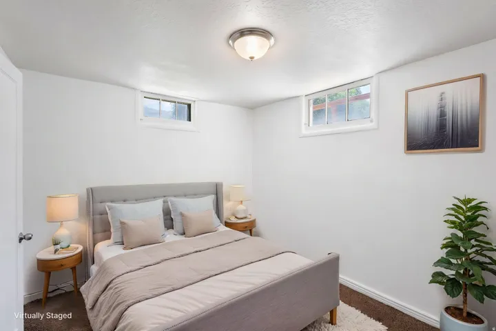 White-painted walls complement the brown carpet flooring and two transom windows, virtually staged