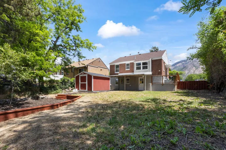 Rear exterior featuring a brick and siding facade, a ground-level deck, and a walk-out basement
