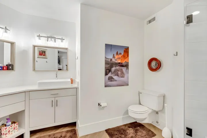 Bathroom featuring a double vanity with stone countertops, a rectangular vessel sink, and an enclosed shower with a glass door