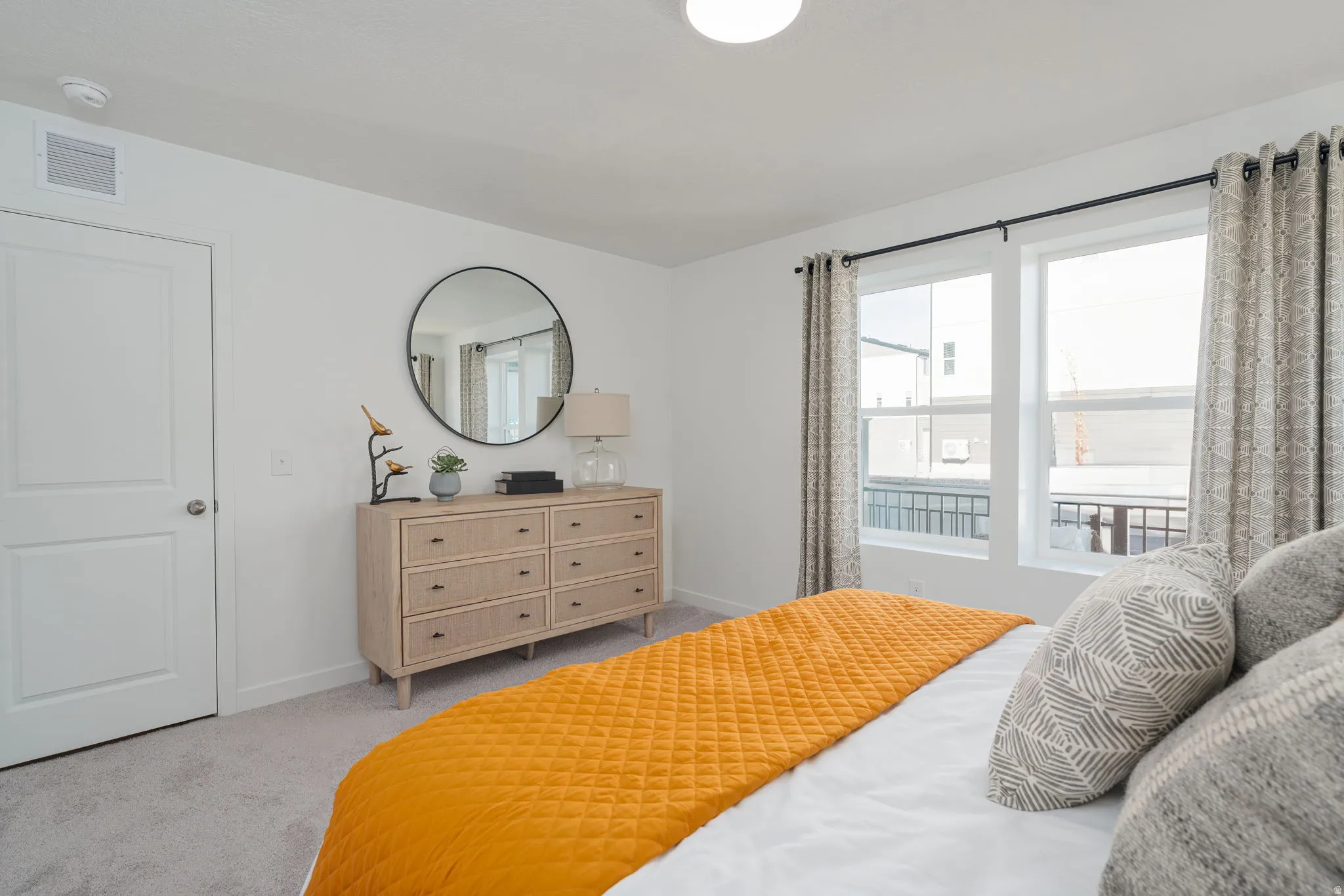 Recessed lighting illuminates a space featuring light gray carpeting, white walls, and a two-panel interior door with brushed nickel hardware