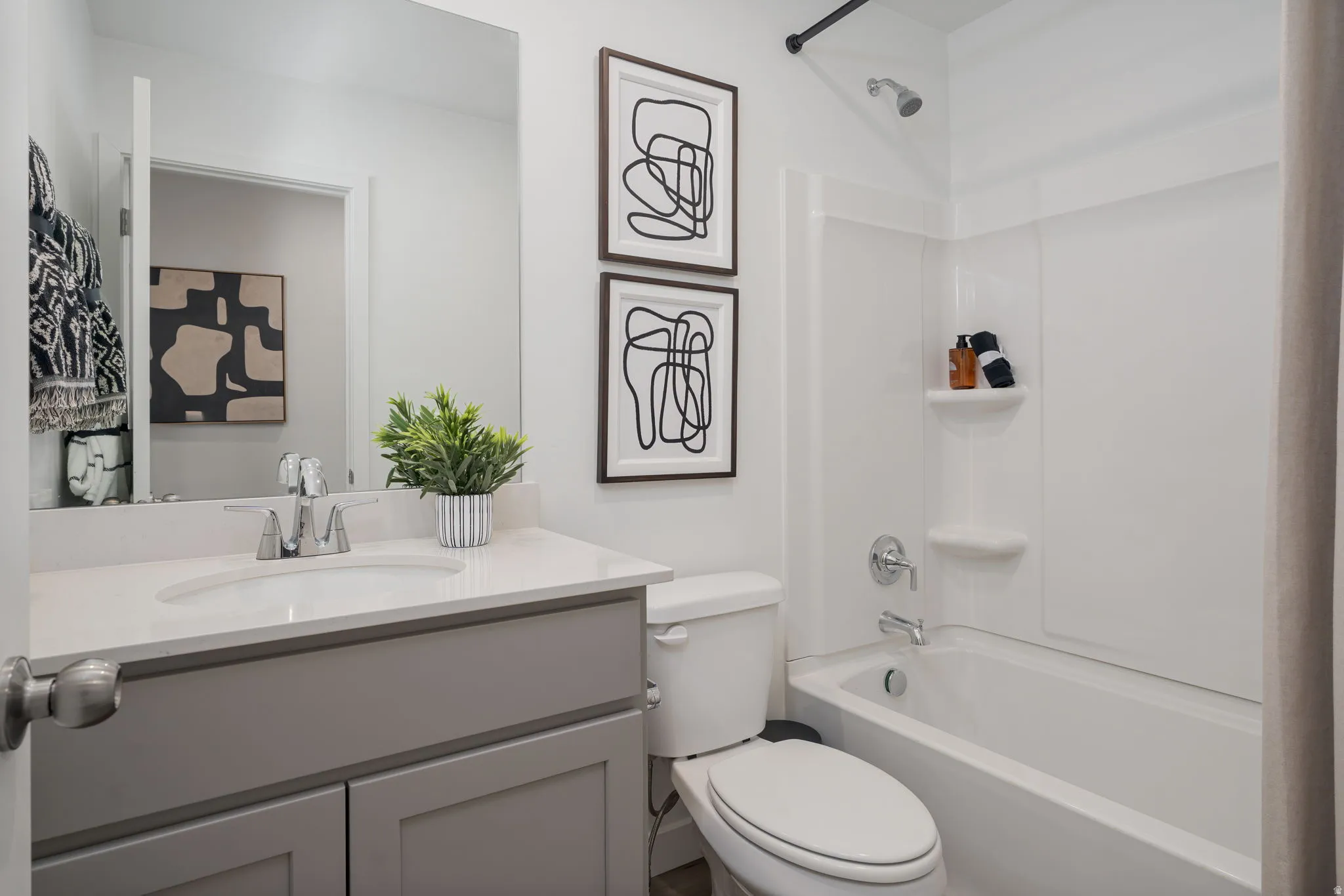 Contemporary bathroom featuring a vanity with a light gray cabinet and white countertop, undermount sink, and chrome faucet