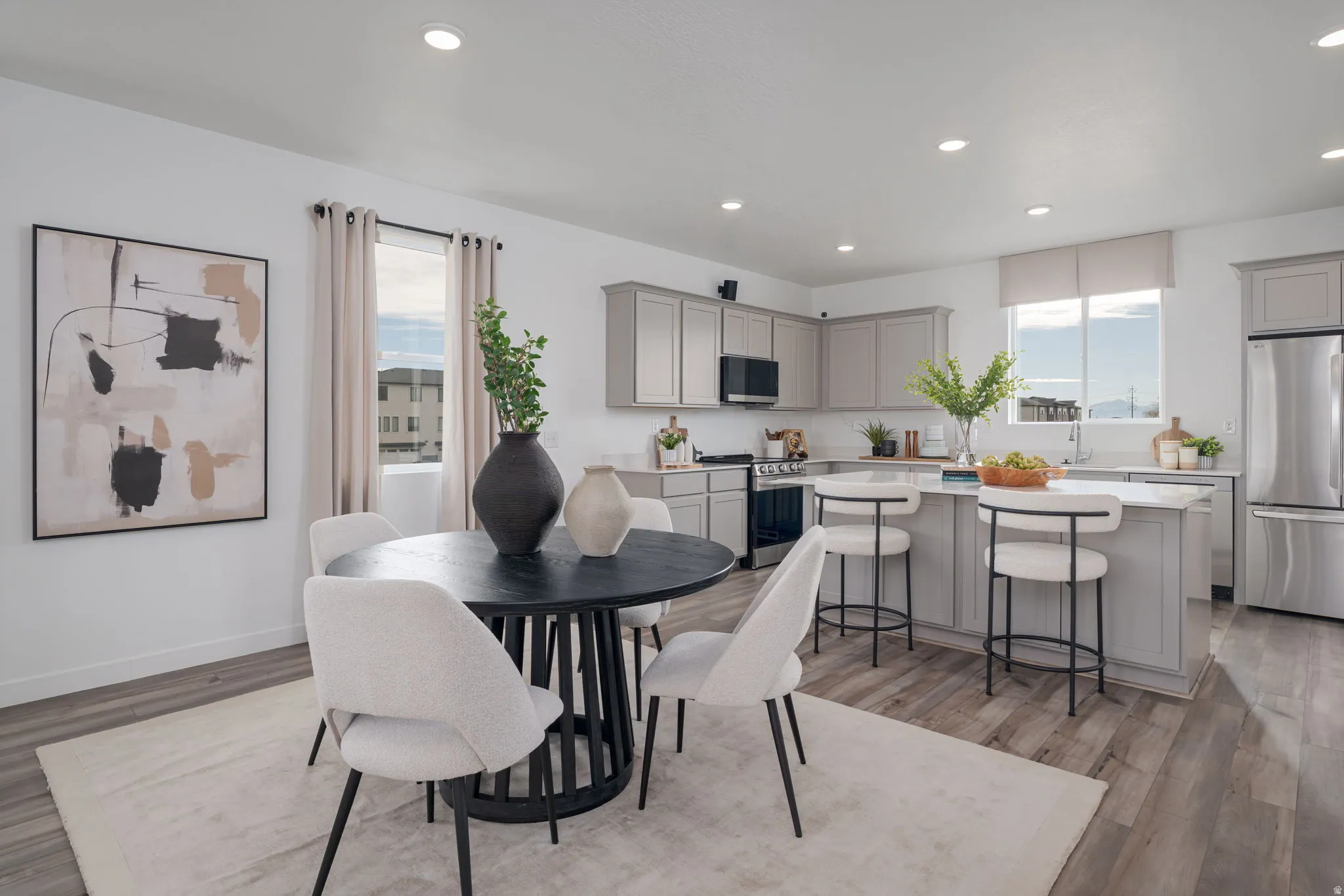 Open-concept dining area and kitchen featuring wood-finish flooring, recessed lighting, and a kitchen island with seating