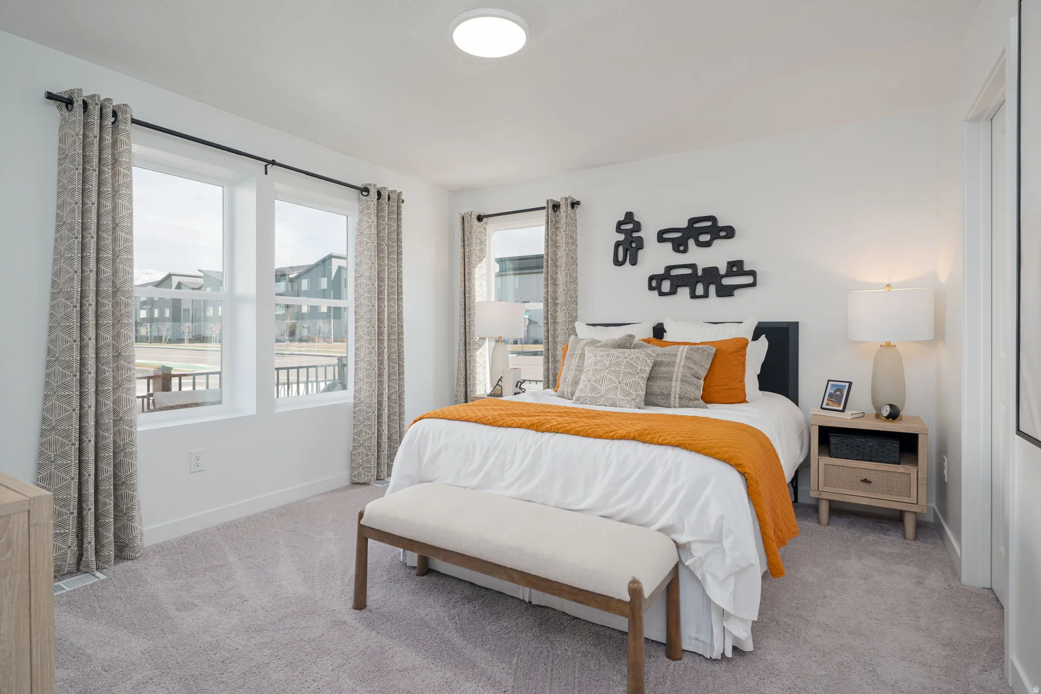 Recessed lighting and two large windows provide ample illumination in this space featuring light gray carpeting and white walls