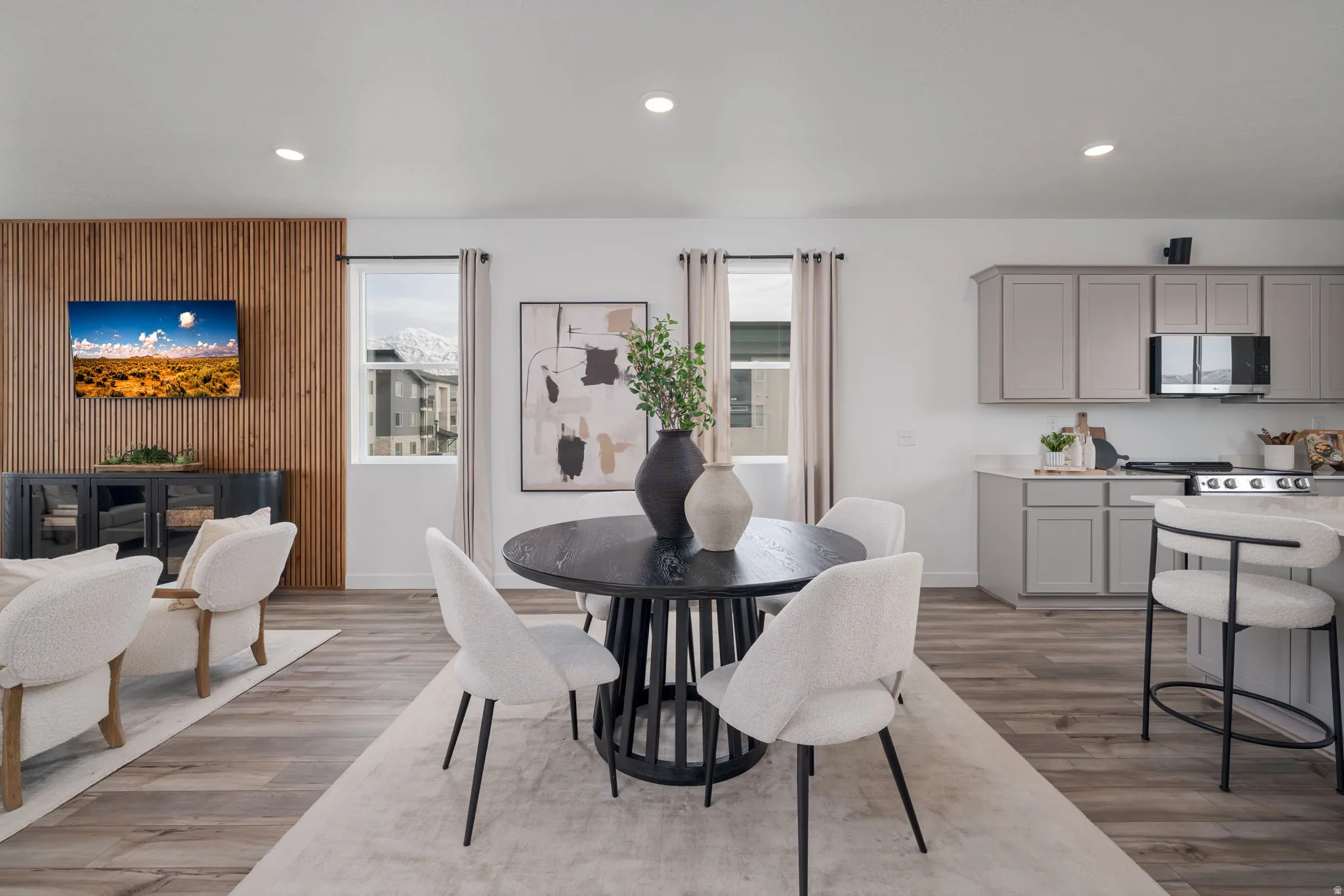 Open-concept living space featuring wood-finish flooring, recessed lighting, and a modern kitchen with light gray cabinetry and stainless steel appliances