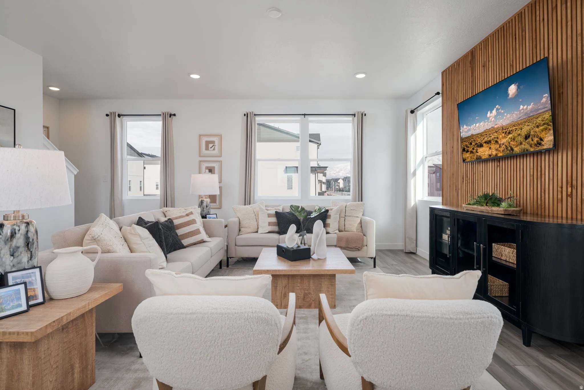 Spacious living area featuring a wood-panel accent wall, recessed lighting, and multiple windows