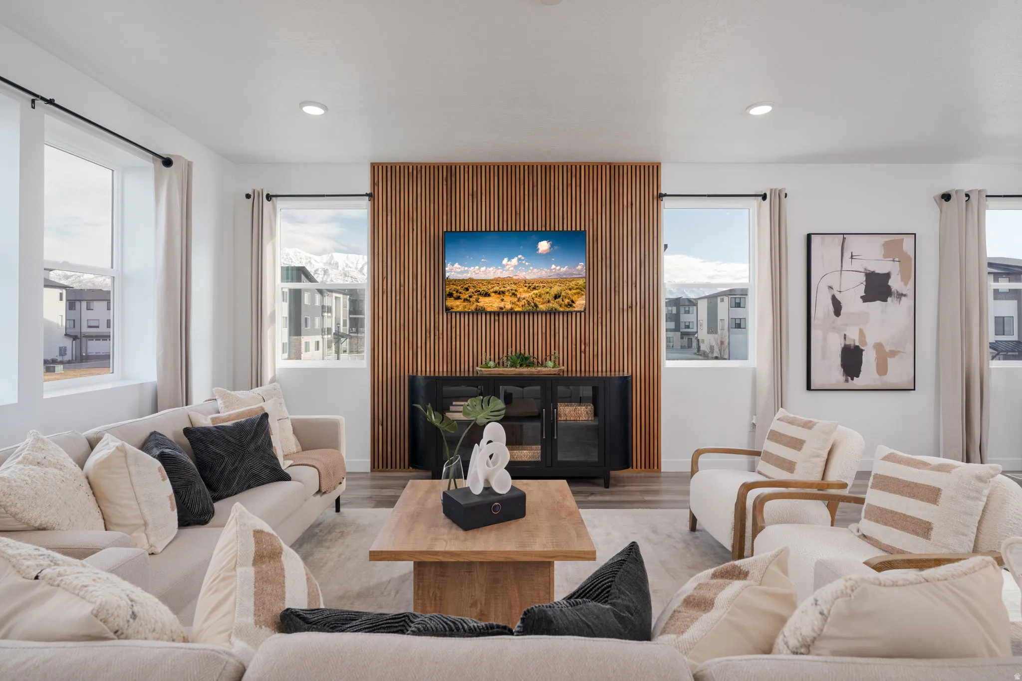 Open-concept living space with light wood-finish flooring, recessed lighting, and a prominent wood slat accent wall