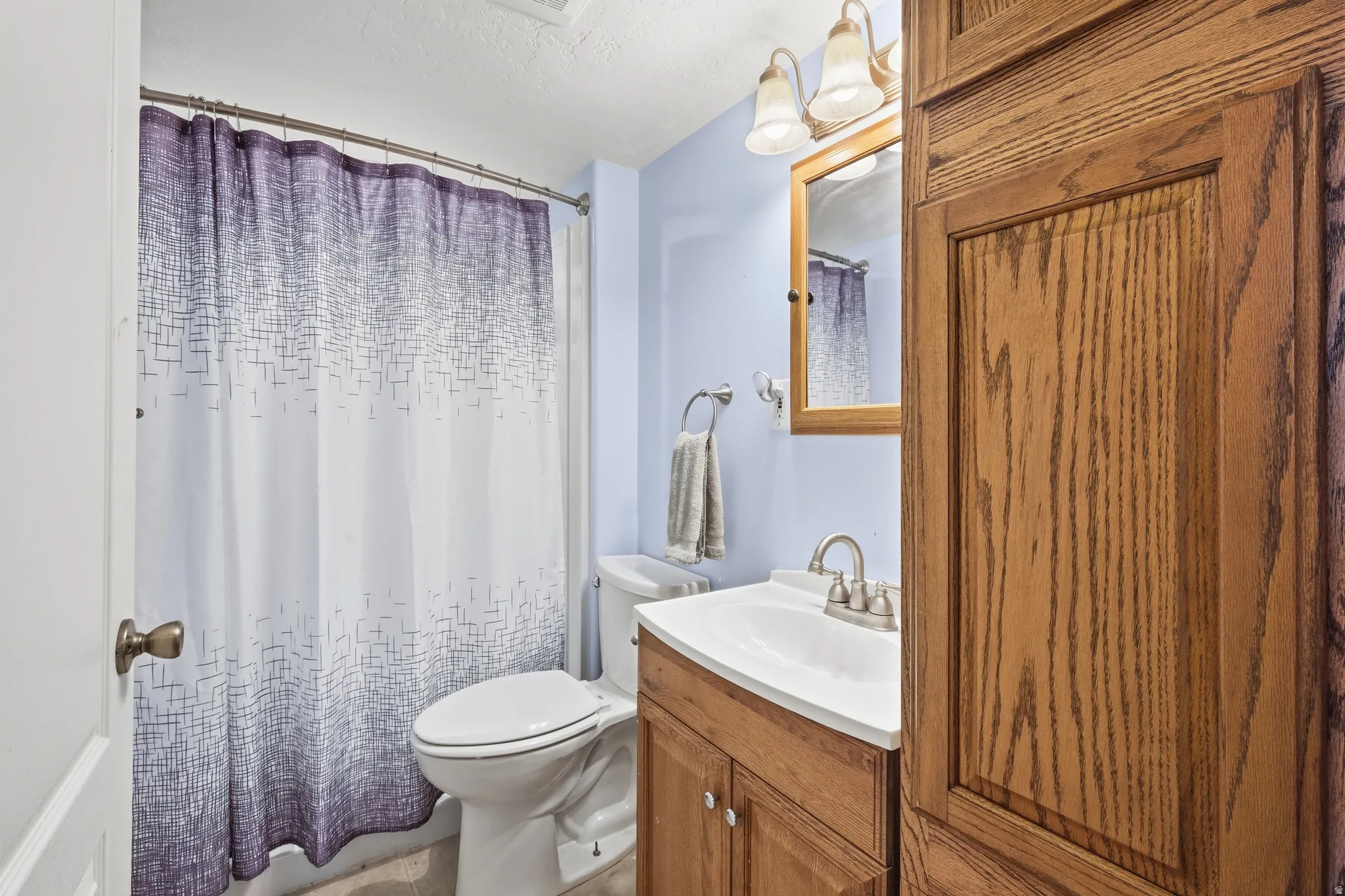 Bathroom featuring a shower-tub combination, a vanity with a white countertop and undermount sink, and a framed mirror