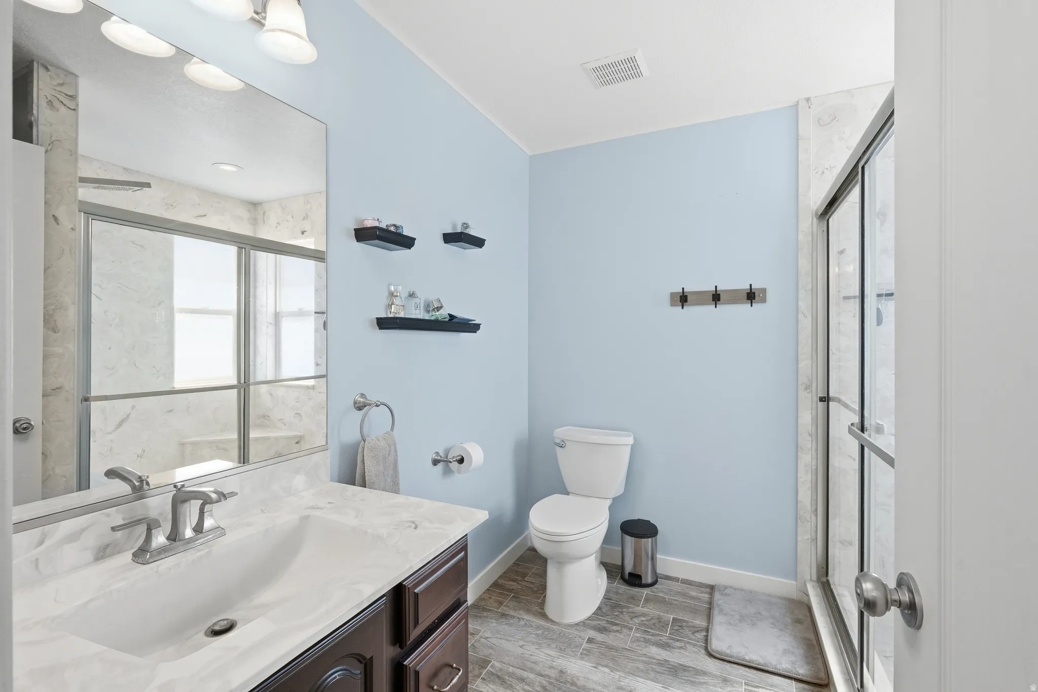 Bathroom featuring a dark wood-finish vanity with a light-colored countertop, an integrated sink, and a brushed nickel faucet