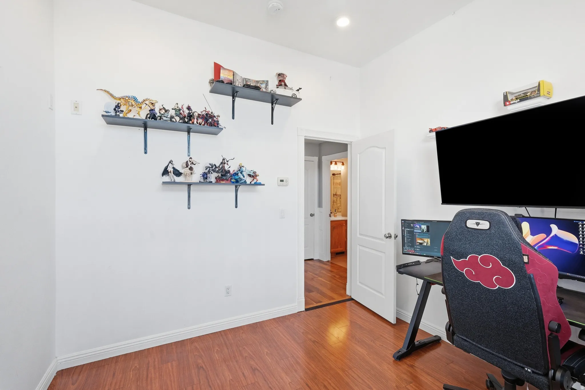 Room featuring wood-finish flooring, white walls, and built-in wall shelving