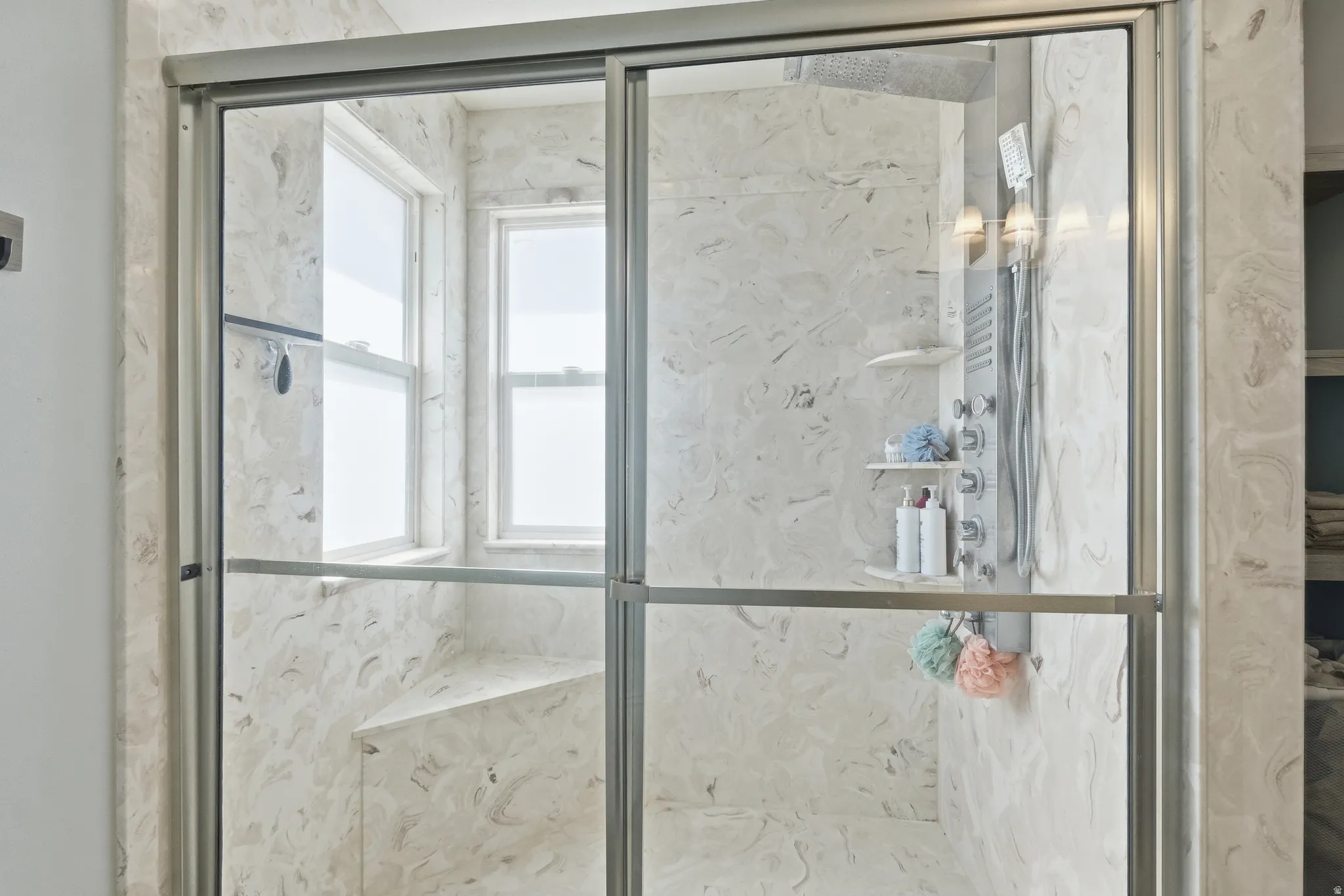 Shower enclosure featuring full-height glass doors and a built-in bench