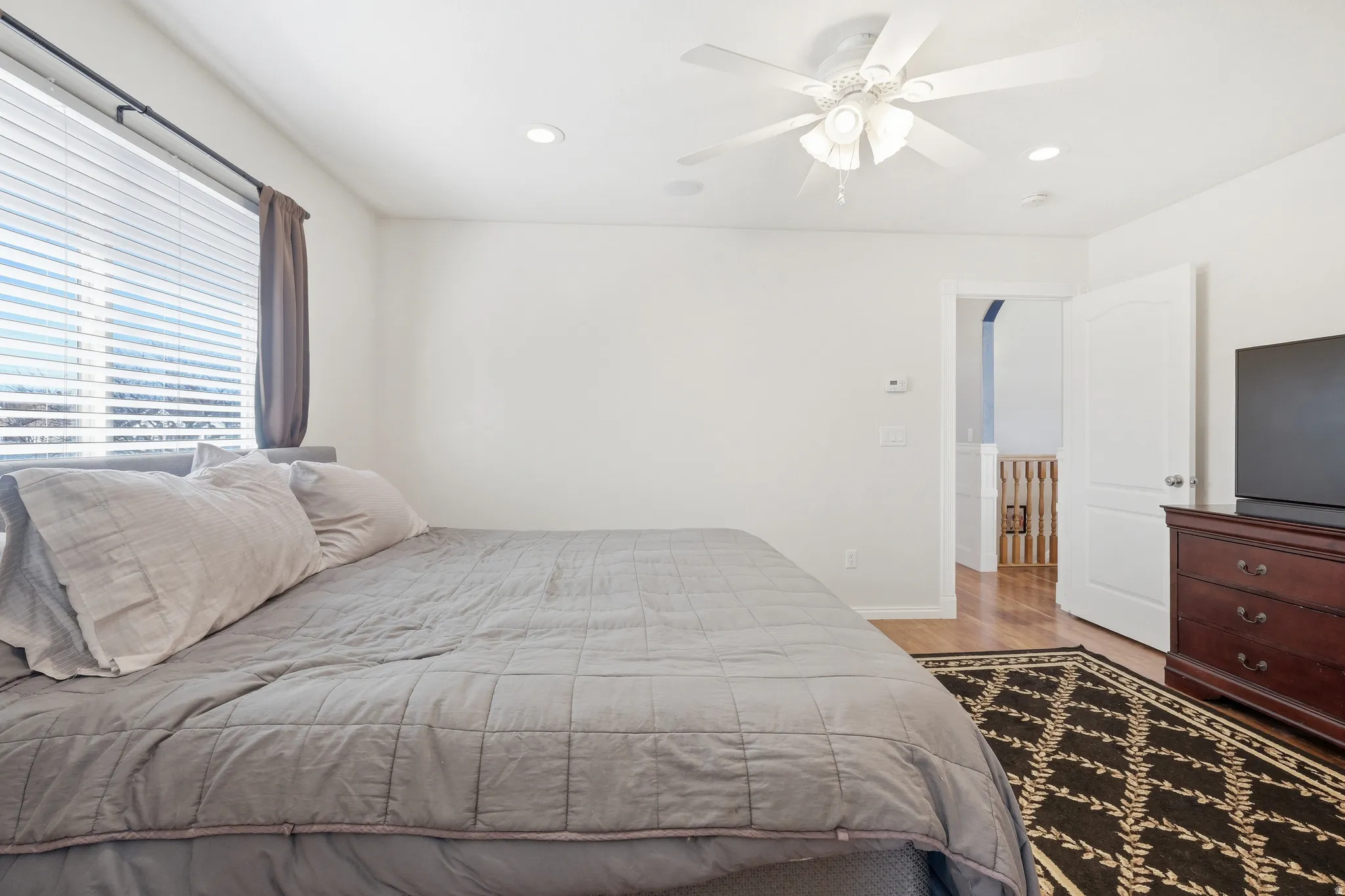 Bedroom featuring a large window with blinds and drapes, recessed lighting, and a ceiling fan